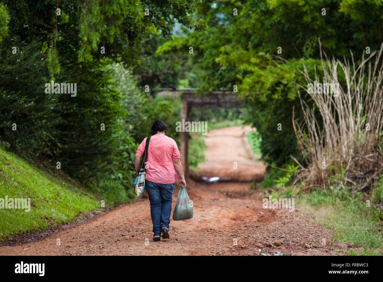Woman walking on a dirt road in the countryside Stock Photo