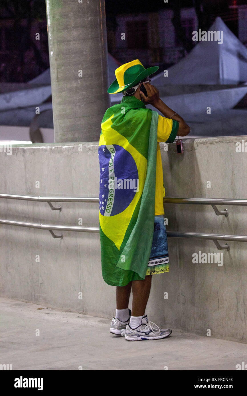 Supporter with Brazilian flag talking on cell surrounding the Estadio do Maracana after retirement Stock Photo