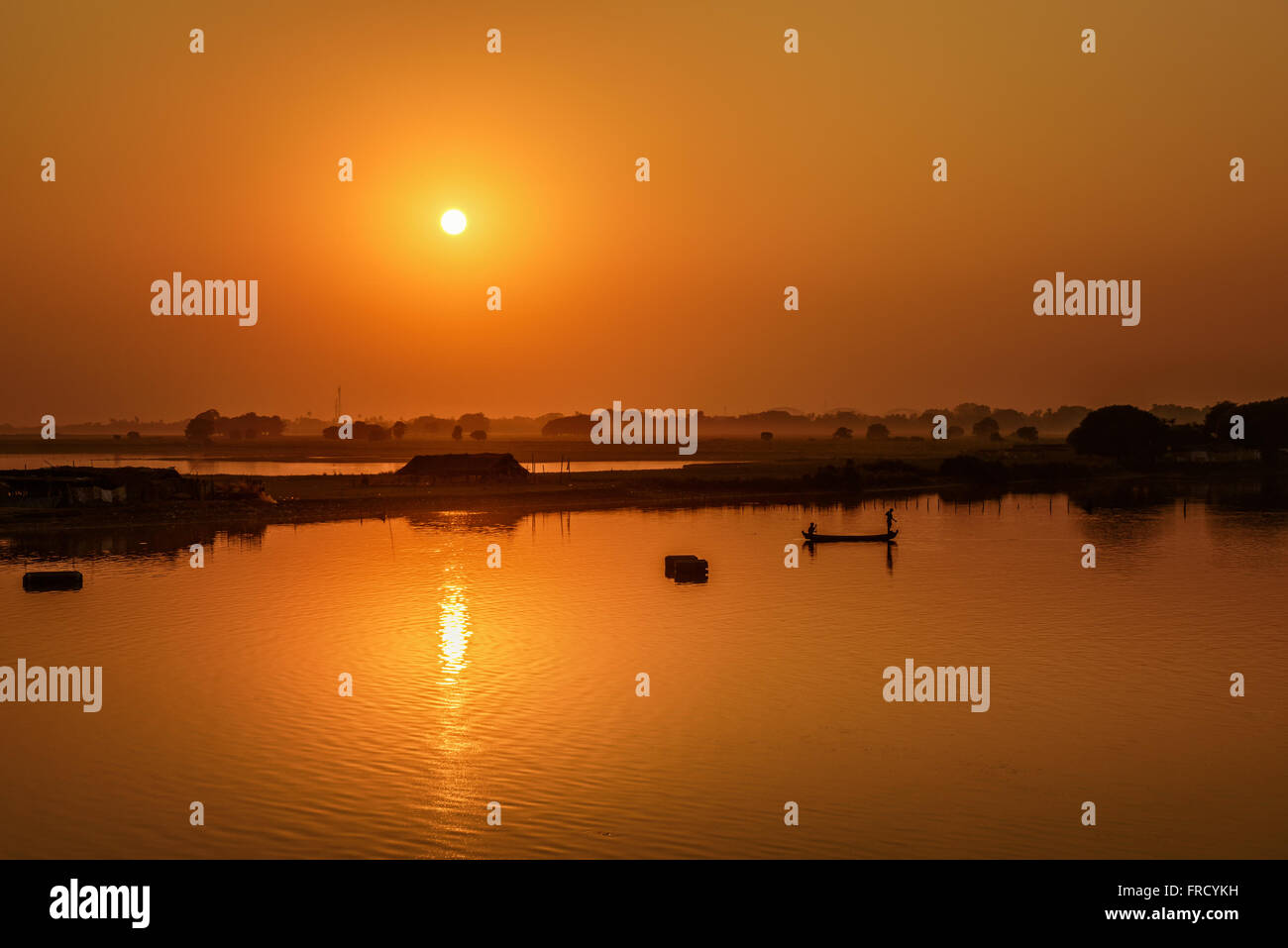 Sunset over the Taungthaman Lake with two fisherman silhouettes near Mandalay in Myanmar Stock Photo