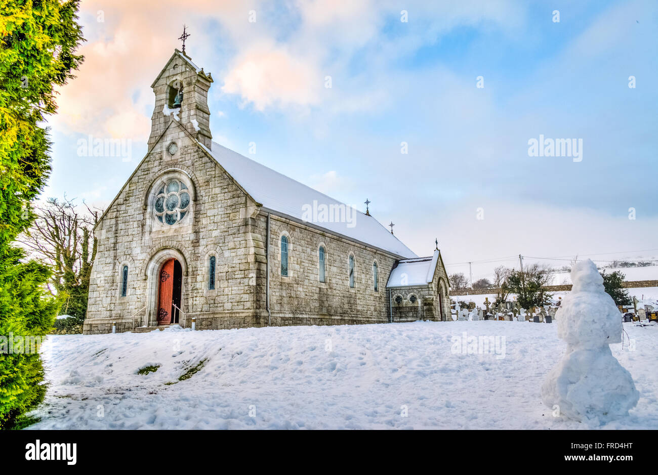 Church in the snow with sunset skies in the background, along with follliage in the corner Stock Photo