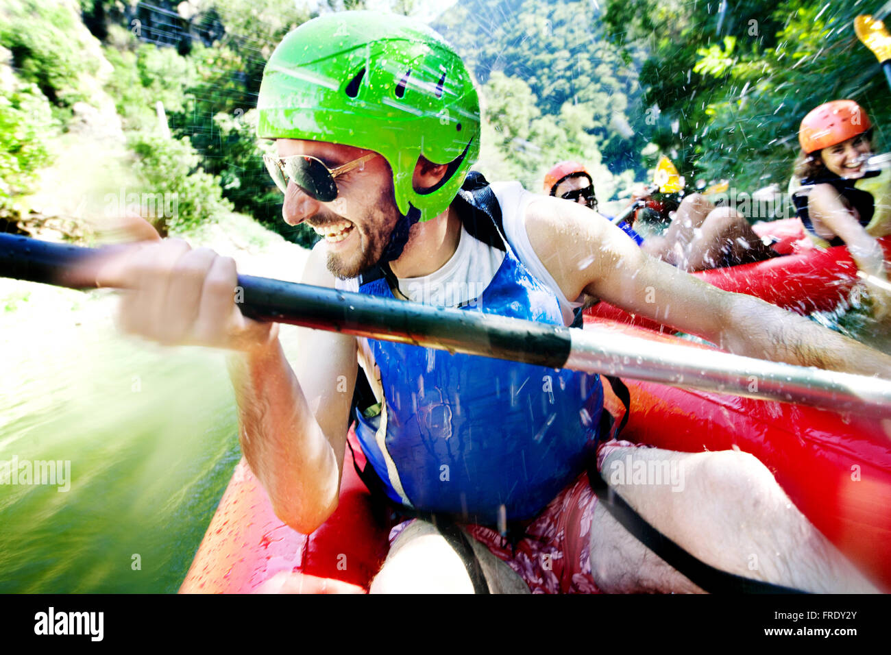 Excited male having fun, laughing on a rafting inflatable canoe being water attacked by a female from another boat. Stock Photo