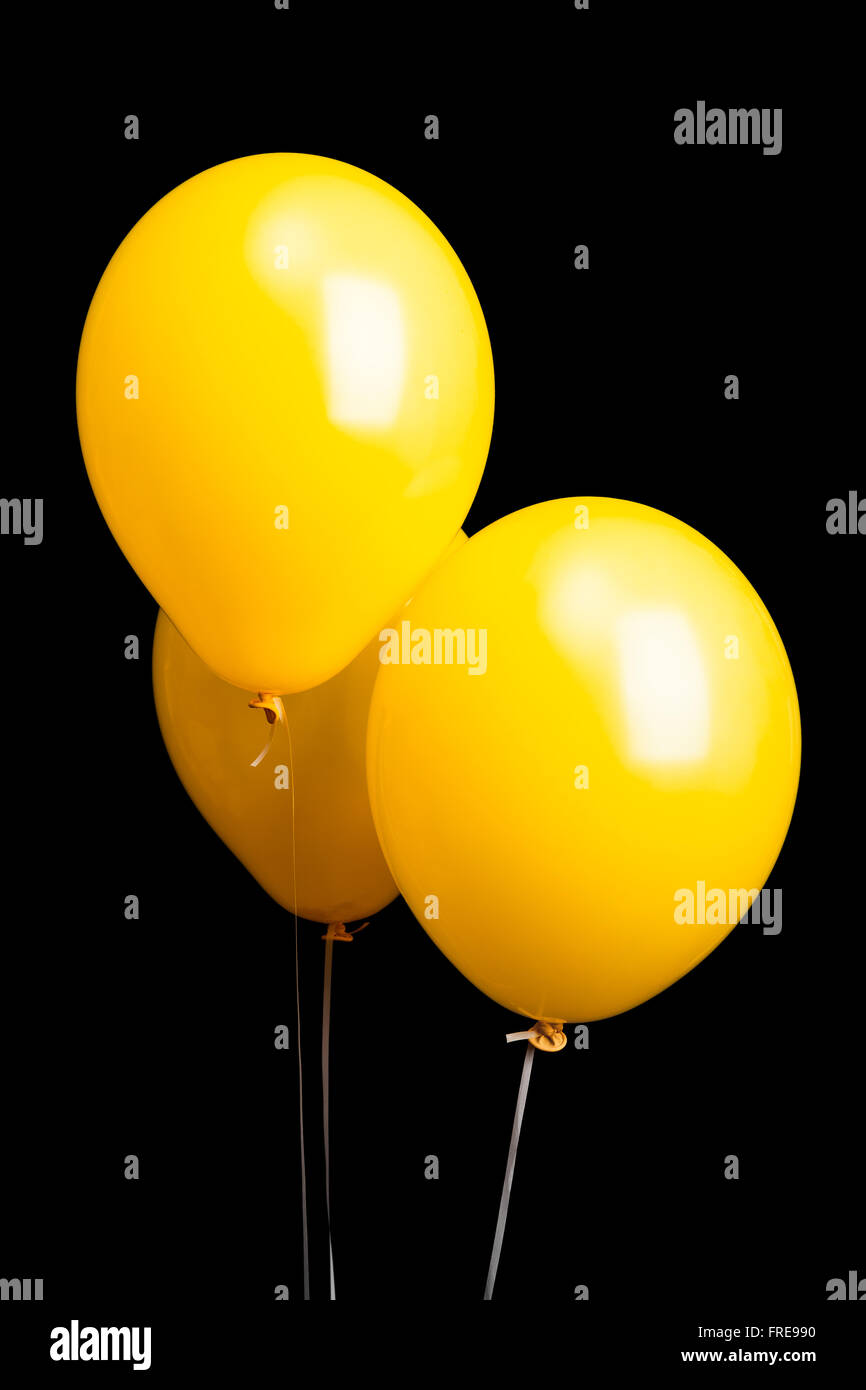 Three yellow balloons isolated on black background Stock Photo