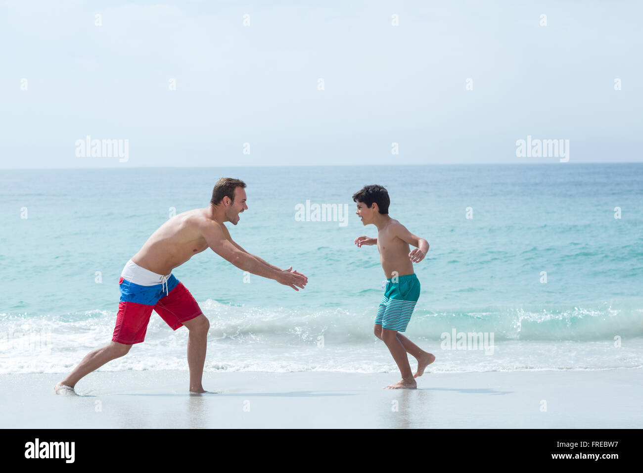 Father chasing son at beach Stock Photo