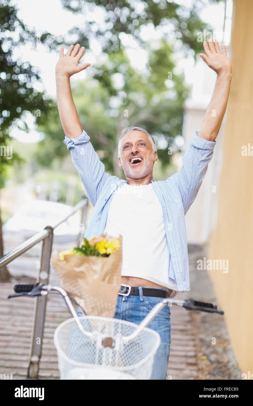 Excited man with arms raised and bicycle Stock Photo