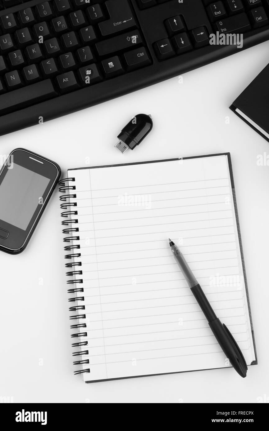 Overhead of white office table with computer keyboard, smartphone,USB,notepad,pen and books Stock Photo