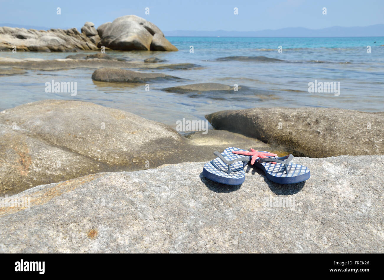 Blue flip flops on sea rock with turquoise sea water in background ...