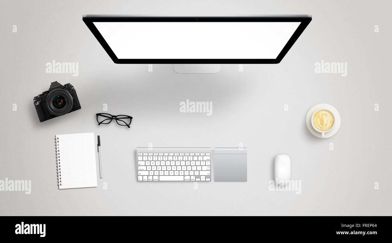 Isolated computer display for mockup on work desk with keyboard, mouse, coffee, camera, notebook, glasses, pencil. Stock Photo