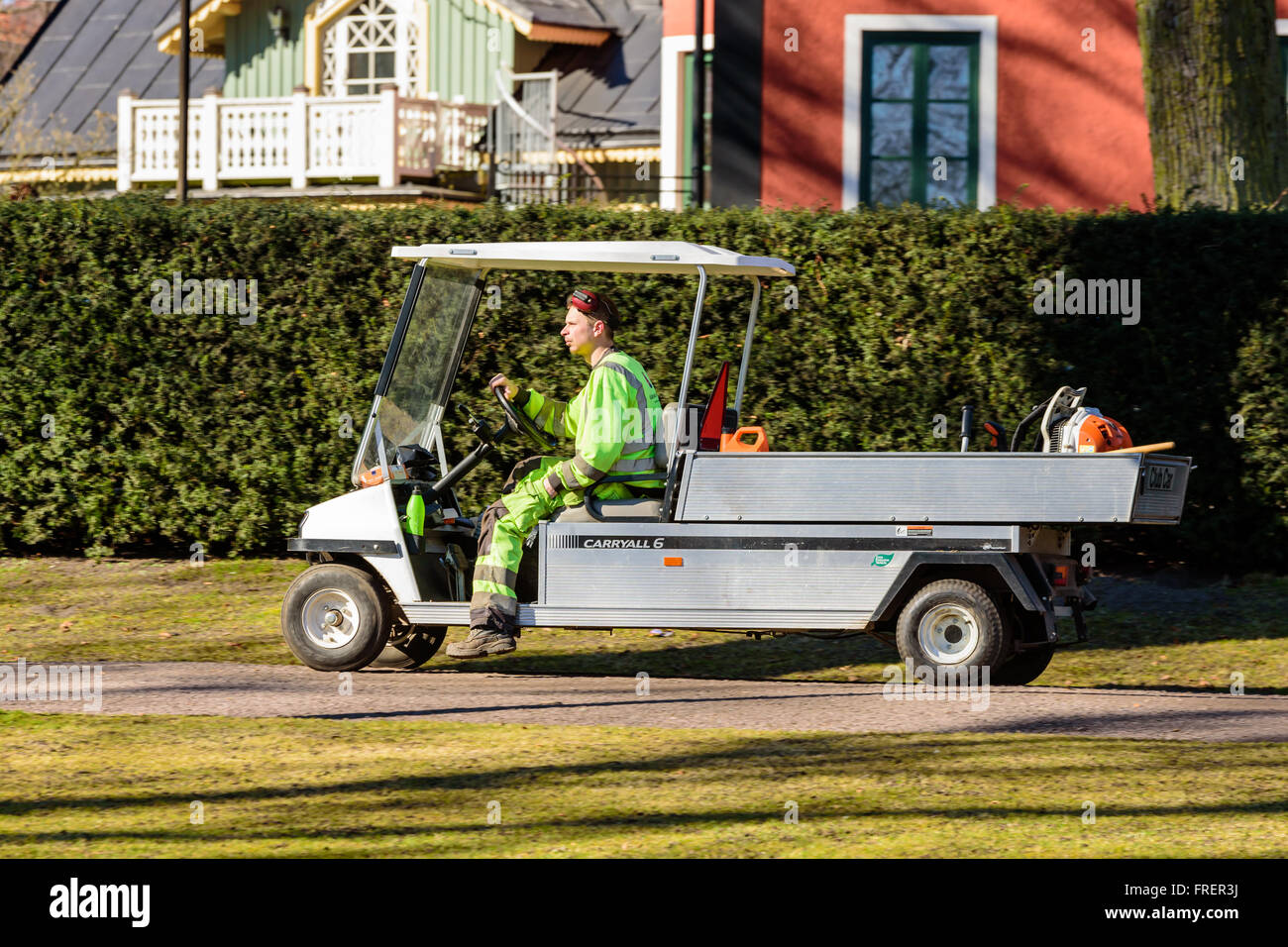 Kalmar, Sweden - March 17, 2016: Male worker in greenish yellow work clothes drive by in a zero emission vehicle, an electric Cl Stock Photo