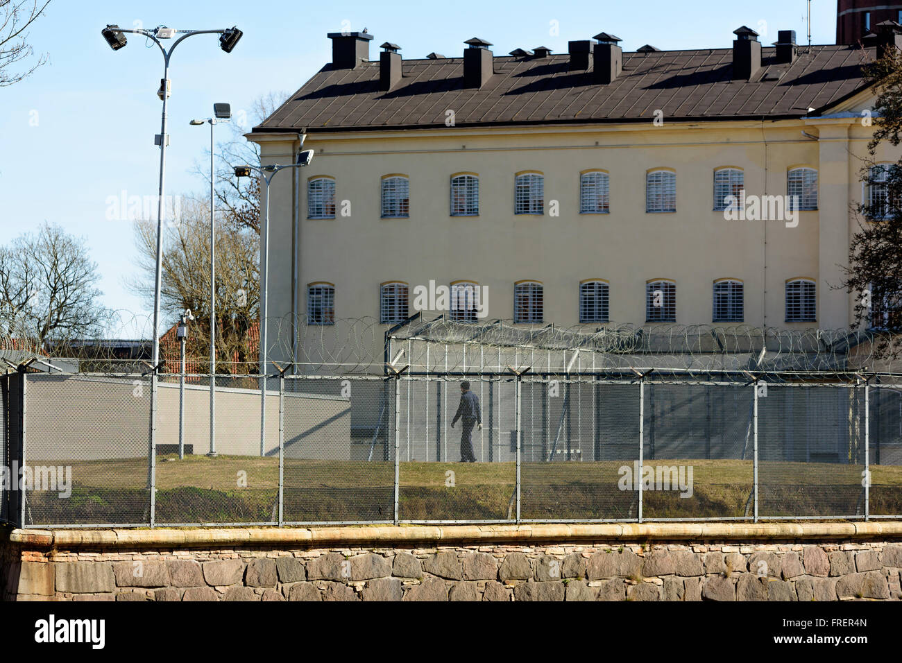 Kalmar, Sweden - March 17, 2016: The prison building with the exercise yard and surrounding barbed and netted fence. People walk Stock Photo