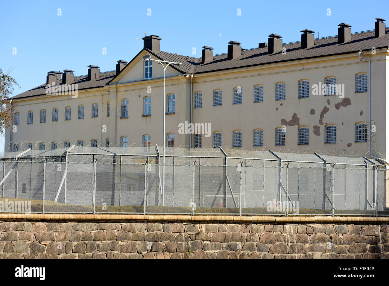 Kalmar, Sweden - March 17, 2016: The prison building with the exercise yard and surrounding barbed and netted fence. People walk Stock Photo