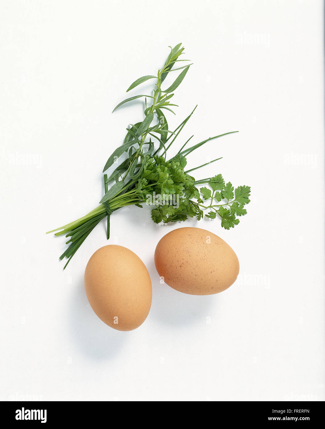 Classic french omelette: Two whole eggs beside a bunch of fresh herbs Stock Photo