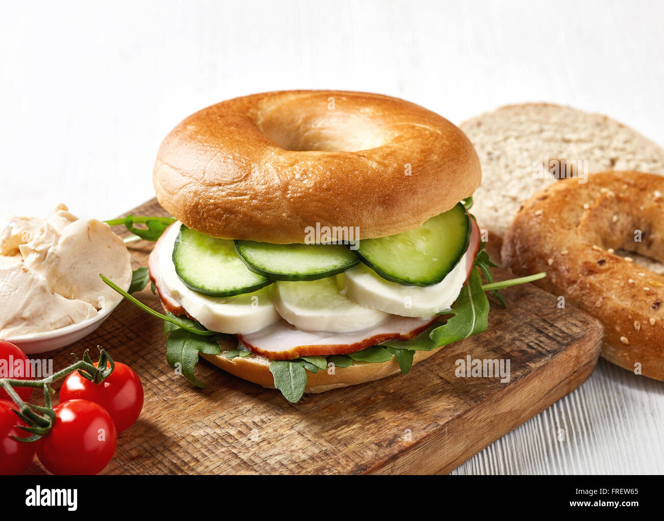 Fresh bagel sandwich on wooden cutting board Stock Photo
