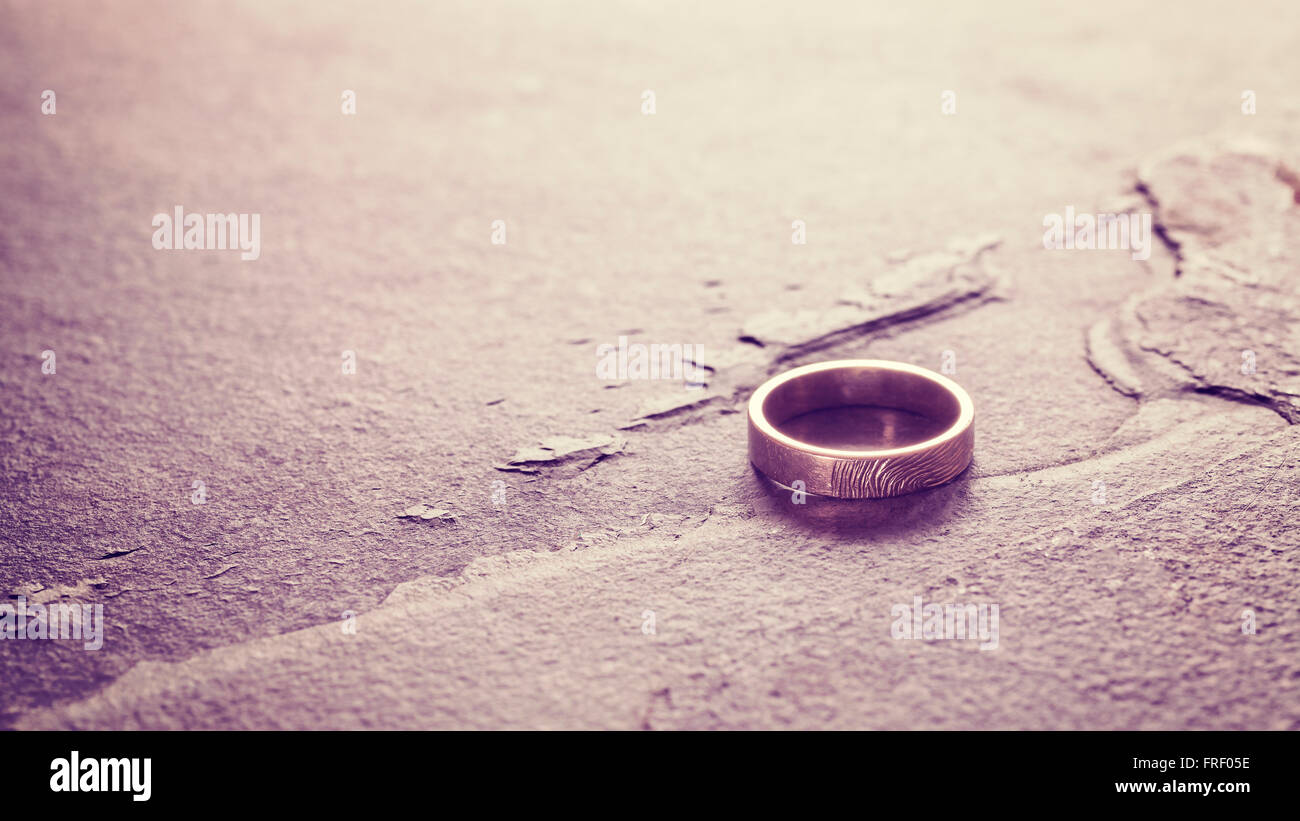 Vintage toned single weeding ring on stone background, conceptual picture. Stock Photo