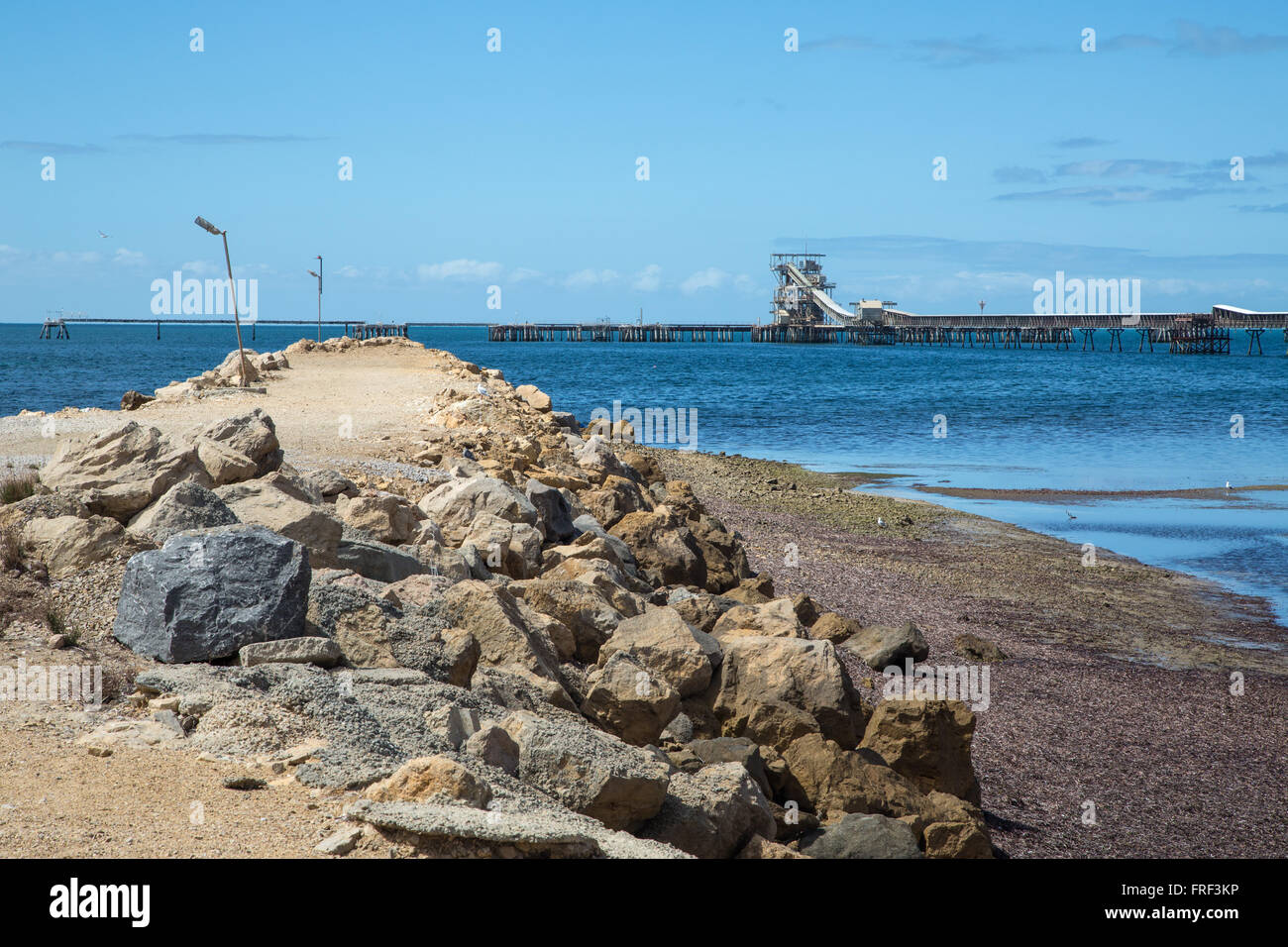newly built rock embankment projecting into smooth sea with jetty Stock Photo