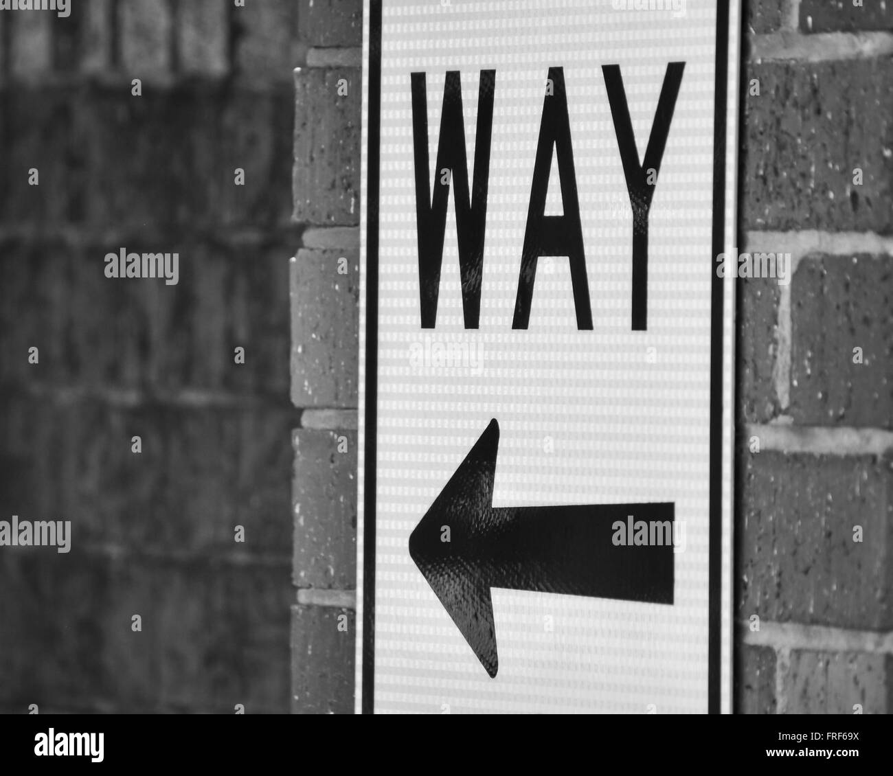 Sign with Arrow on Brick Wall in Black and White Stock Photo