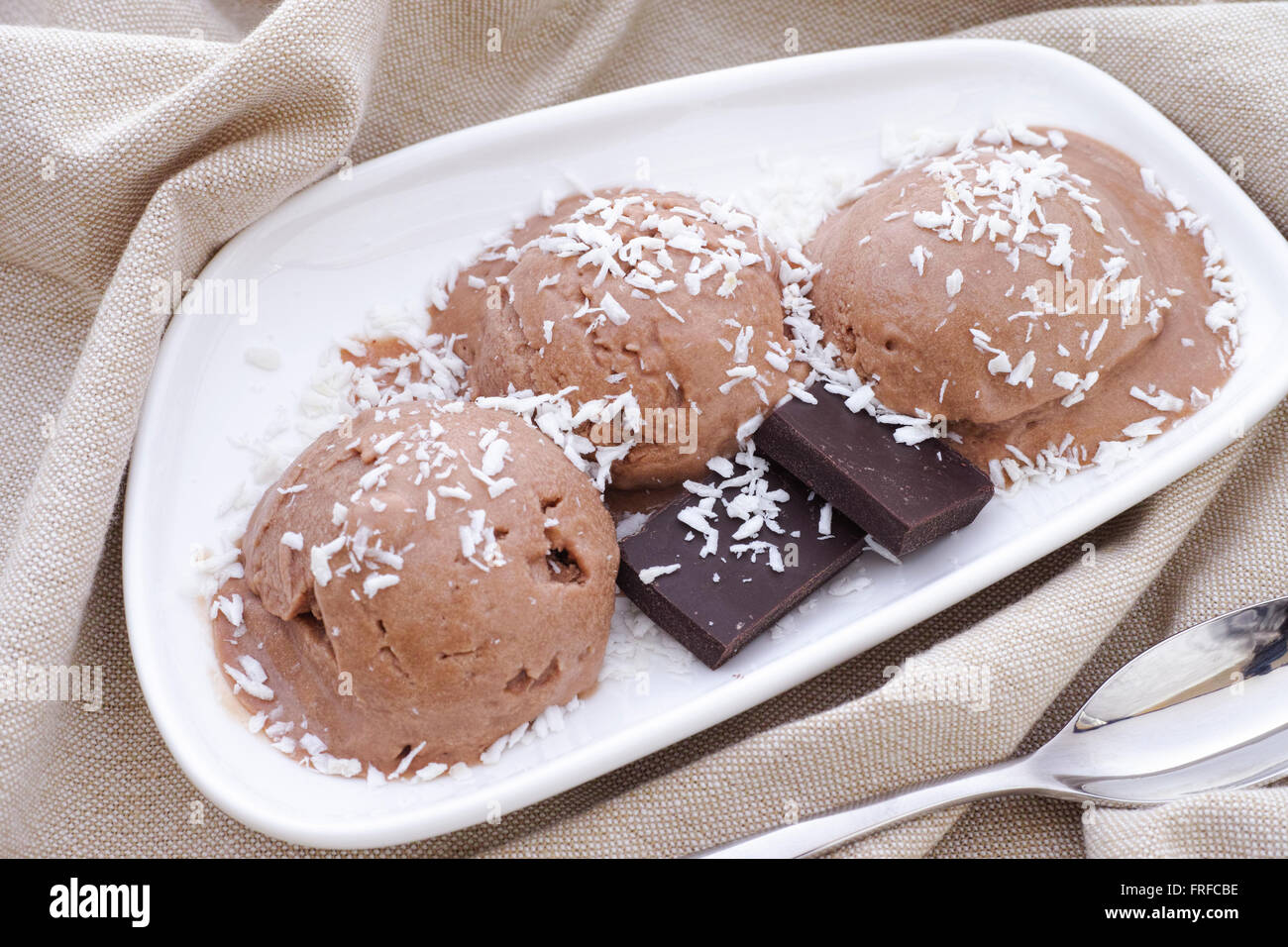 Three scoops of vegan chocolate ice cream with coconut sprinkles and pieces of broken chocolate. (coconut cream, cocoa powder) Stock Photo