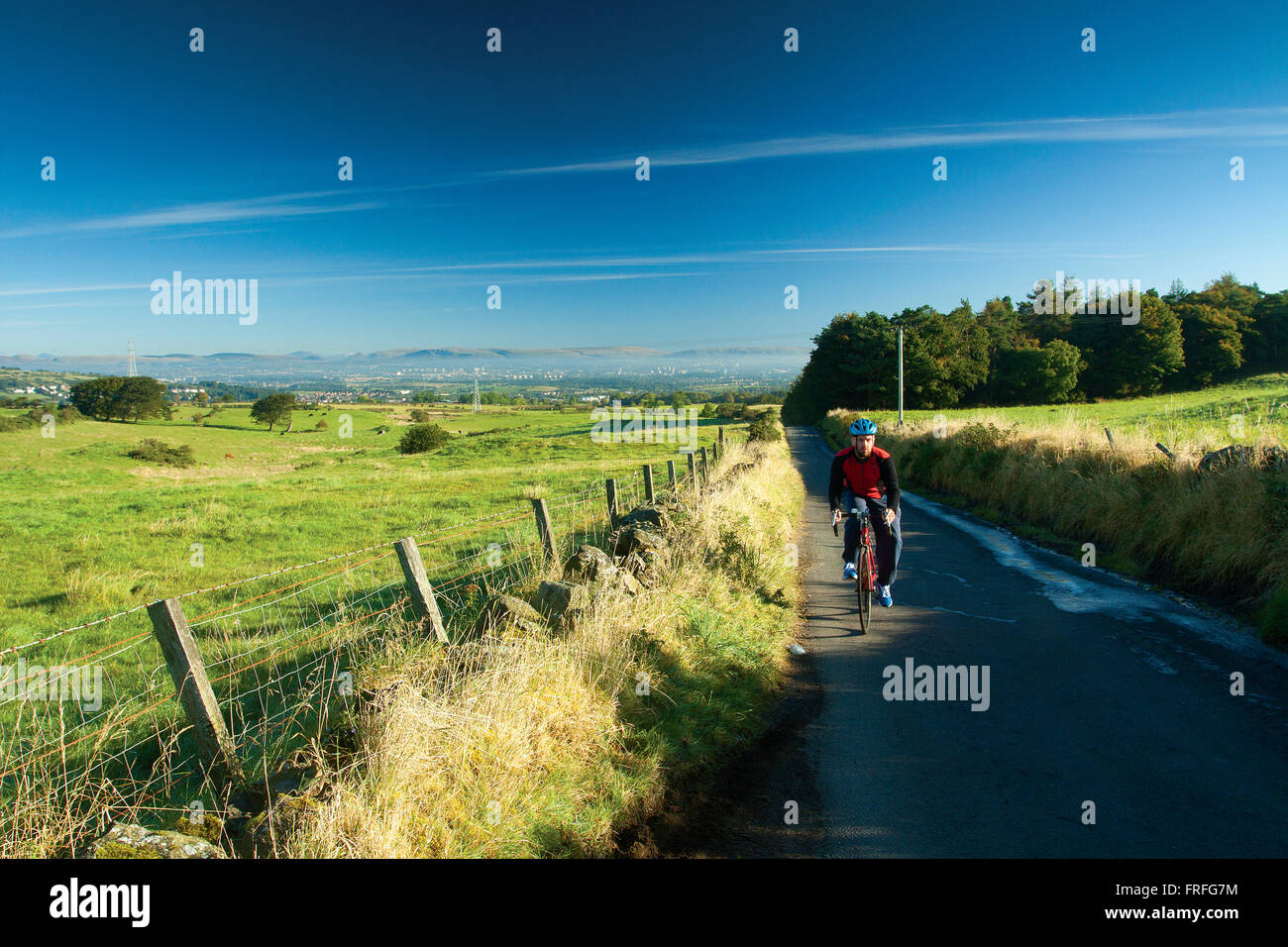 A cyclist cycling above Barrhead and Neilston, East Renfrewshire Stock