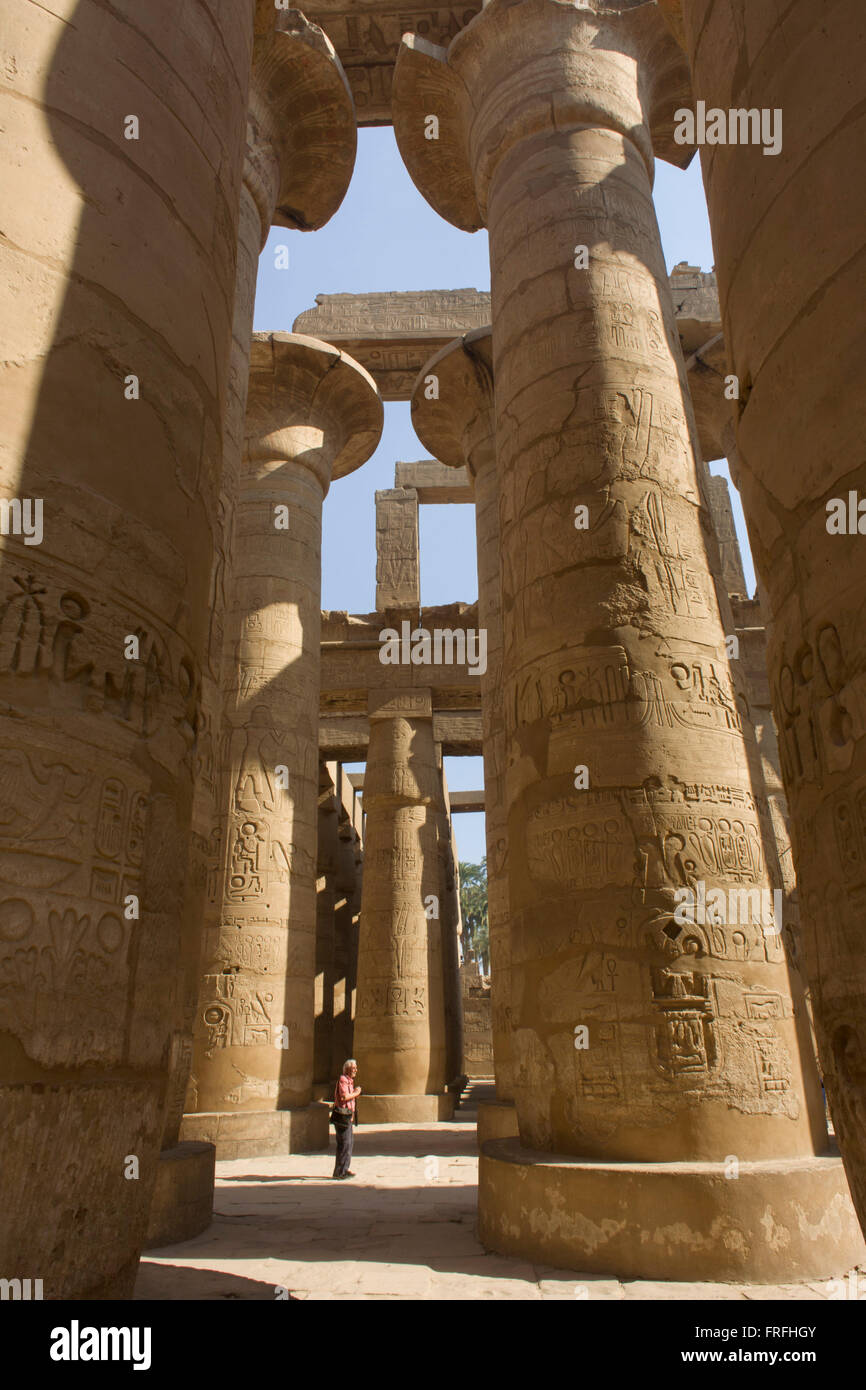The tall columns in the Hypostyle hall at the Temple of Amun at Karnak, Luxor, Nile Valley, Egypt. The Karnak Temple Complex is the largest religious building ever made, covering about 200 acres. It comprises a vast mix of decayed temples, chapels, pylons, and other buildings built over 2,000 years and dedicated to the Theban triad of Amun, Mut, and Khonsu. The Hypostyle hall, at 54,000 square feet (16,459 meters) and featuring 134 columns, is still the largest room of any religious building in the world. Stock Photo