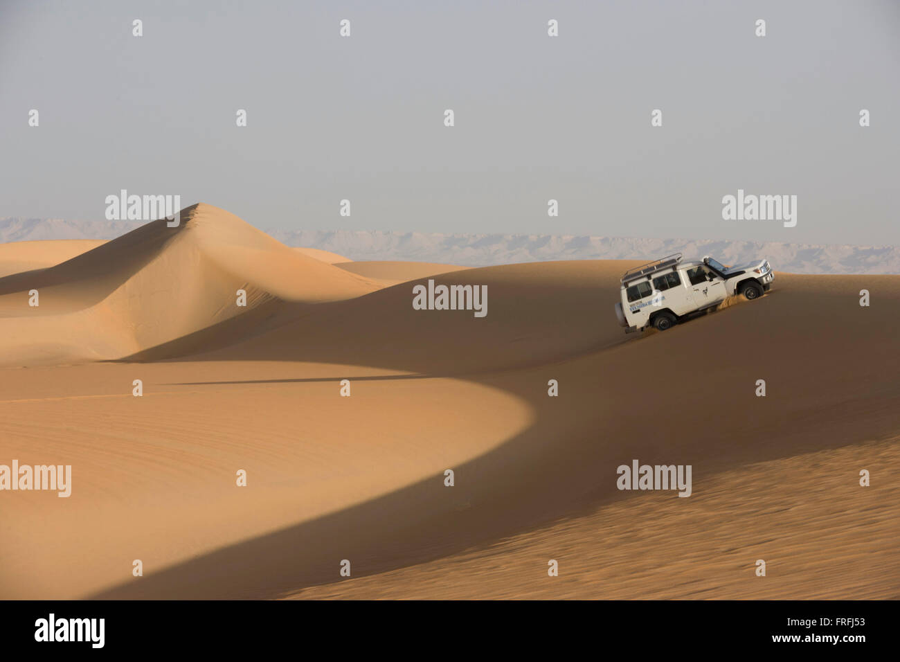 A 4x4 desert expedition vehicle climbs a sand dune at al-Galamun, near Dahkla Oasis, Western Desert, Egypt. The Western Desert covers an area of some 700,000 km2, thereby accounting for around two-thirds of Egypt's total land area. Dakhla Oasis is one of the seven oases of Egypt's Western Desert (part of the Libyan Desert). It lies in the New Valley Governorate, 350 km (220 mi.) and measures approximately 80 km (50 mi) from east to west and 25 km (16 mi) from north to south. Stock Photo