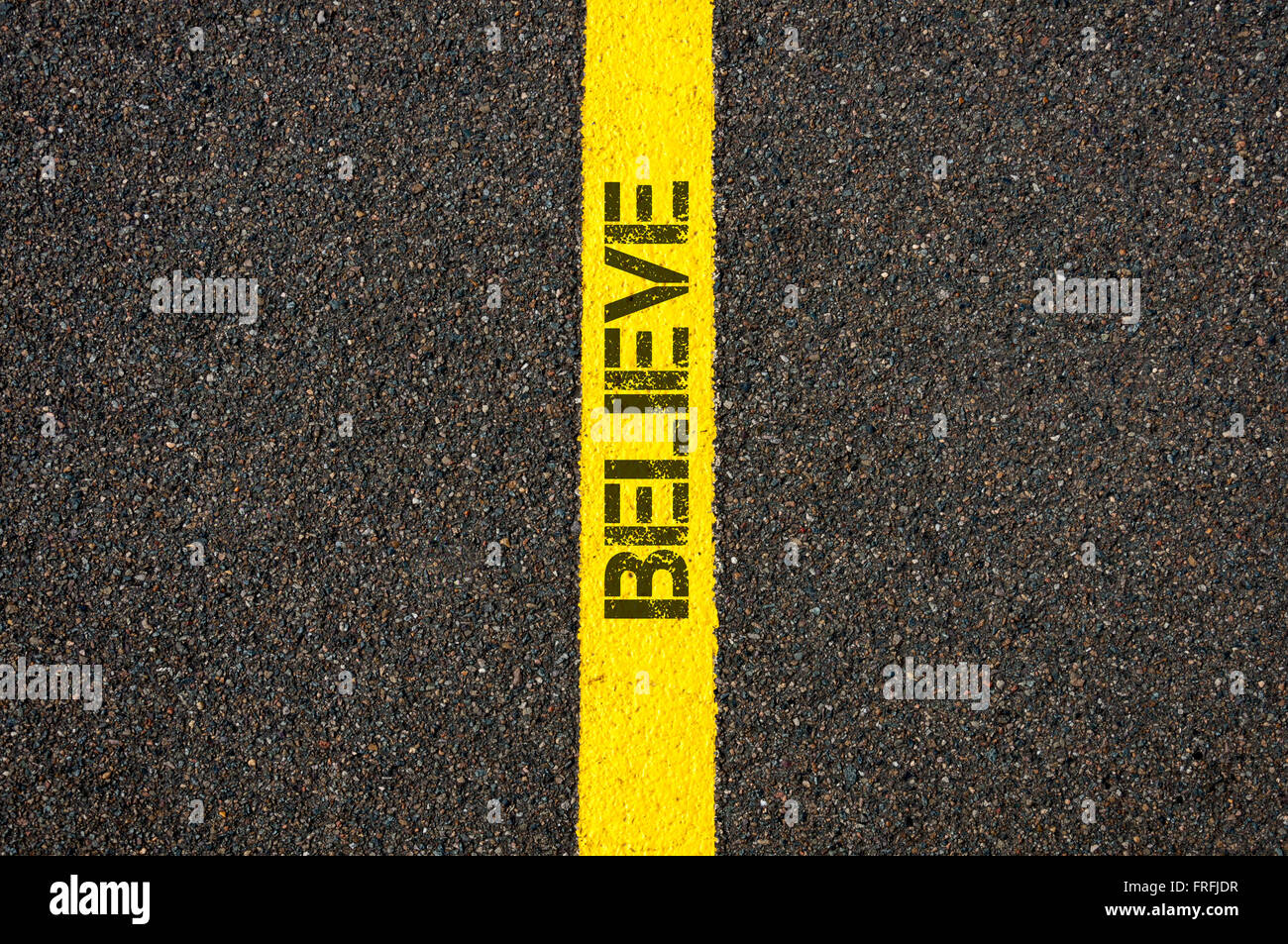 Road marking yellow paint dividing line with word BELIEVE, concept image Stock Photo