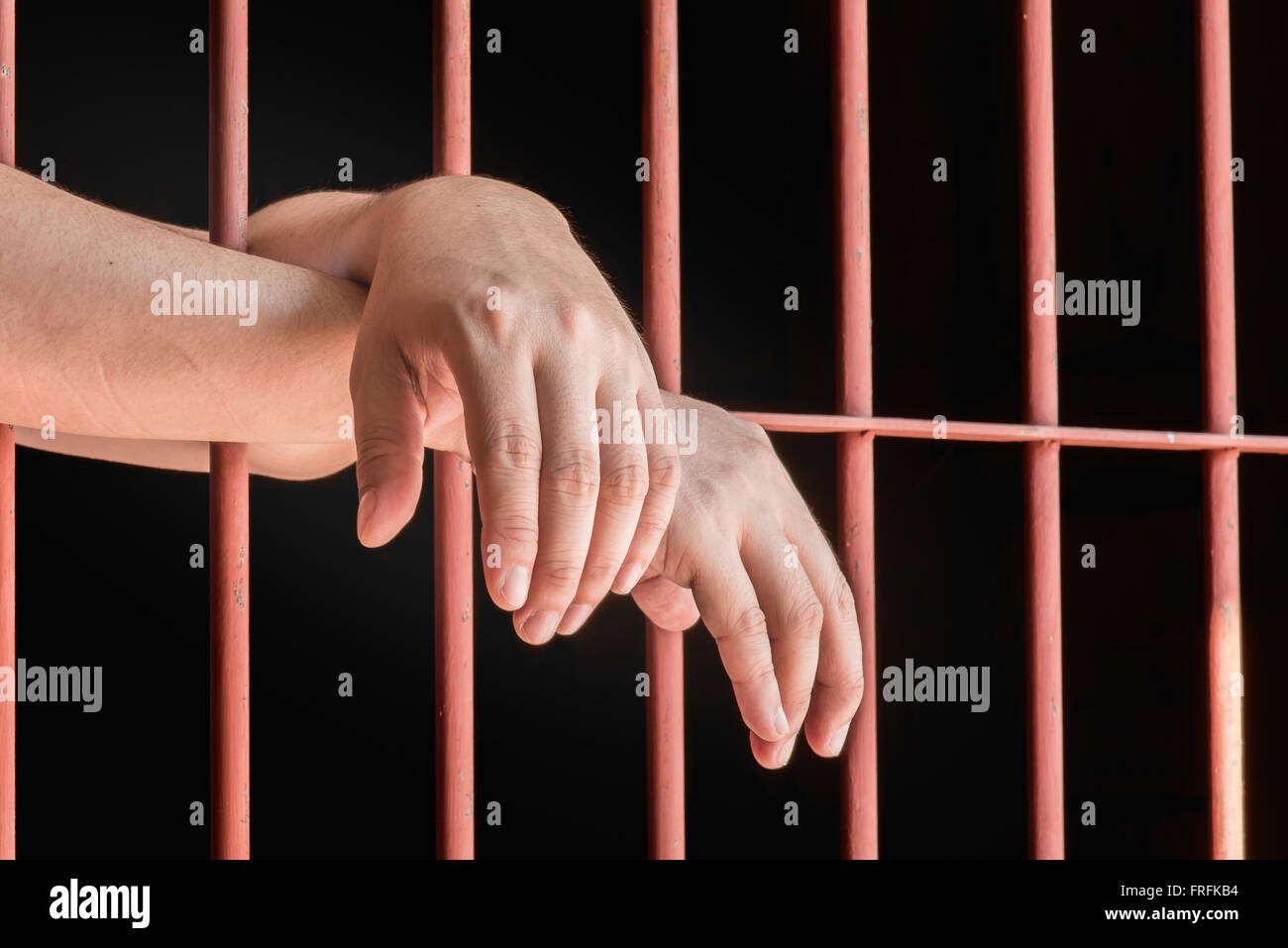 Close up hand of male muslim hanging on bar in jail. Stock Photo