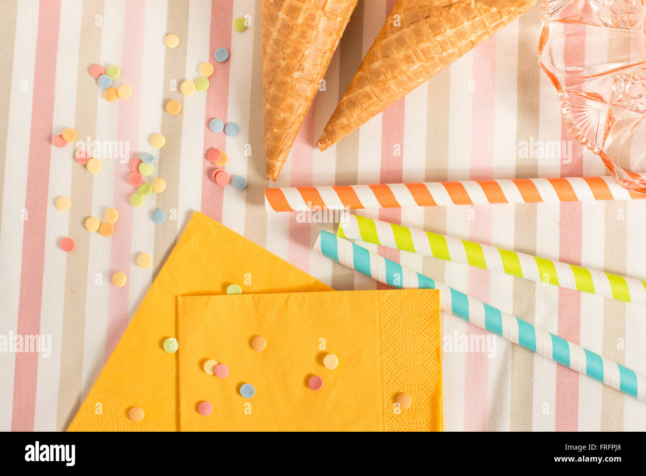 Colorful sugar sprinkles, straws and ice cream cones. Preparation for party or celebration. Concept of food styling. Stock Photo
