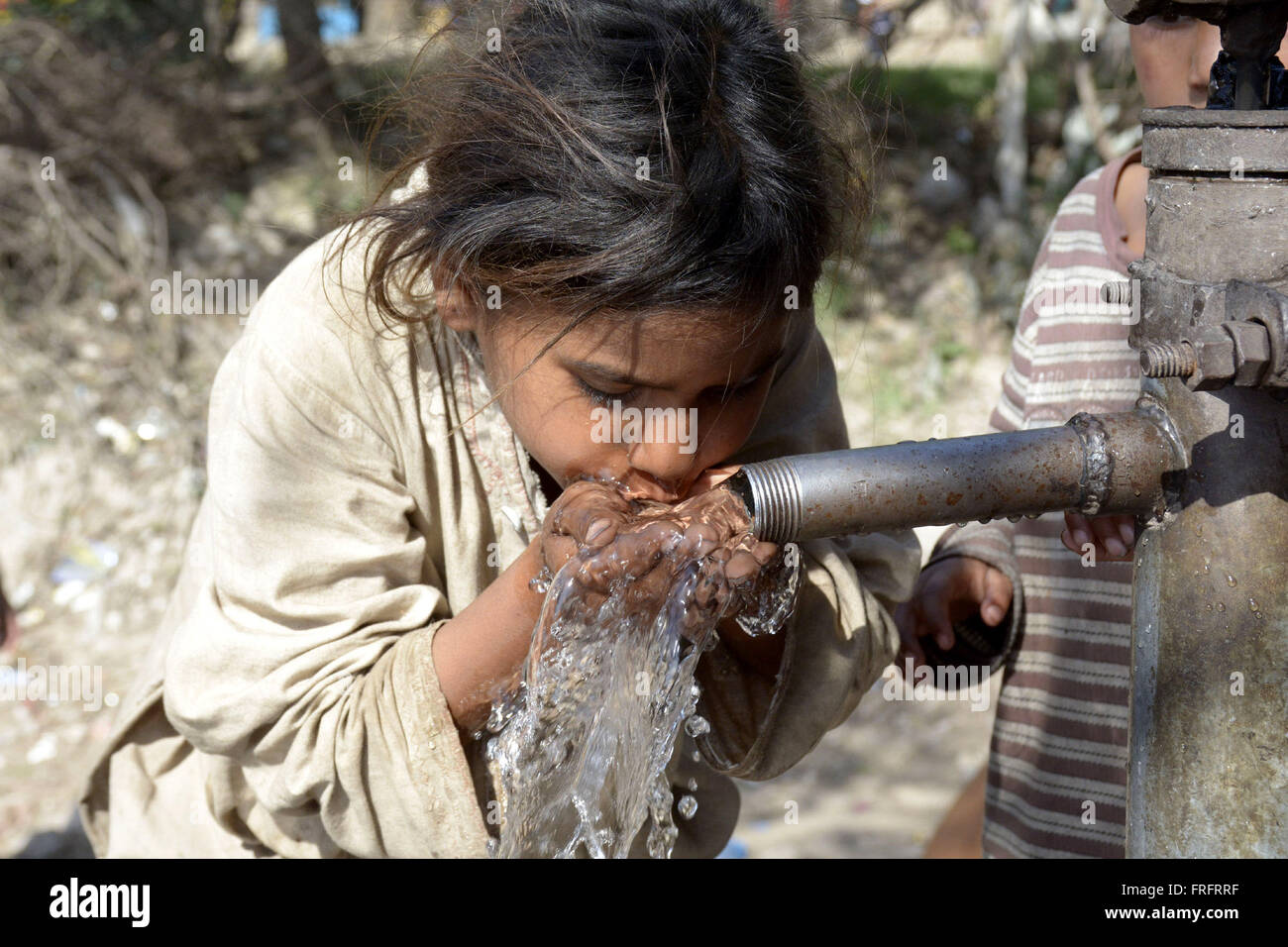 Lahore, Pakistan. 22nd Mar, 2016. A girl drinks water from a water hand pump at a makeshift settlement in Lahore, eastern Pakistan, on March 22, 2016. World Water Day is observed annually on March 22 as a means of highlighting the importance of fresh water. © Sajjad/Xinhua/Alamy Live News Stock Photo