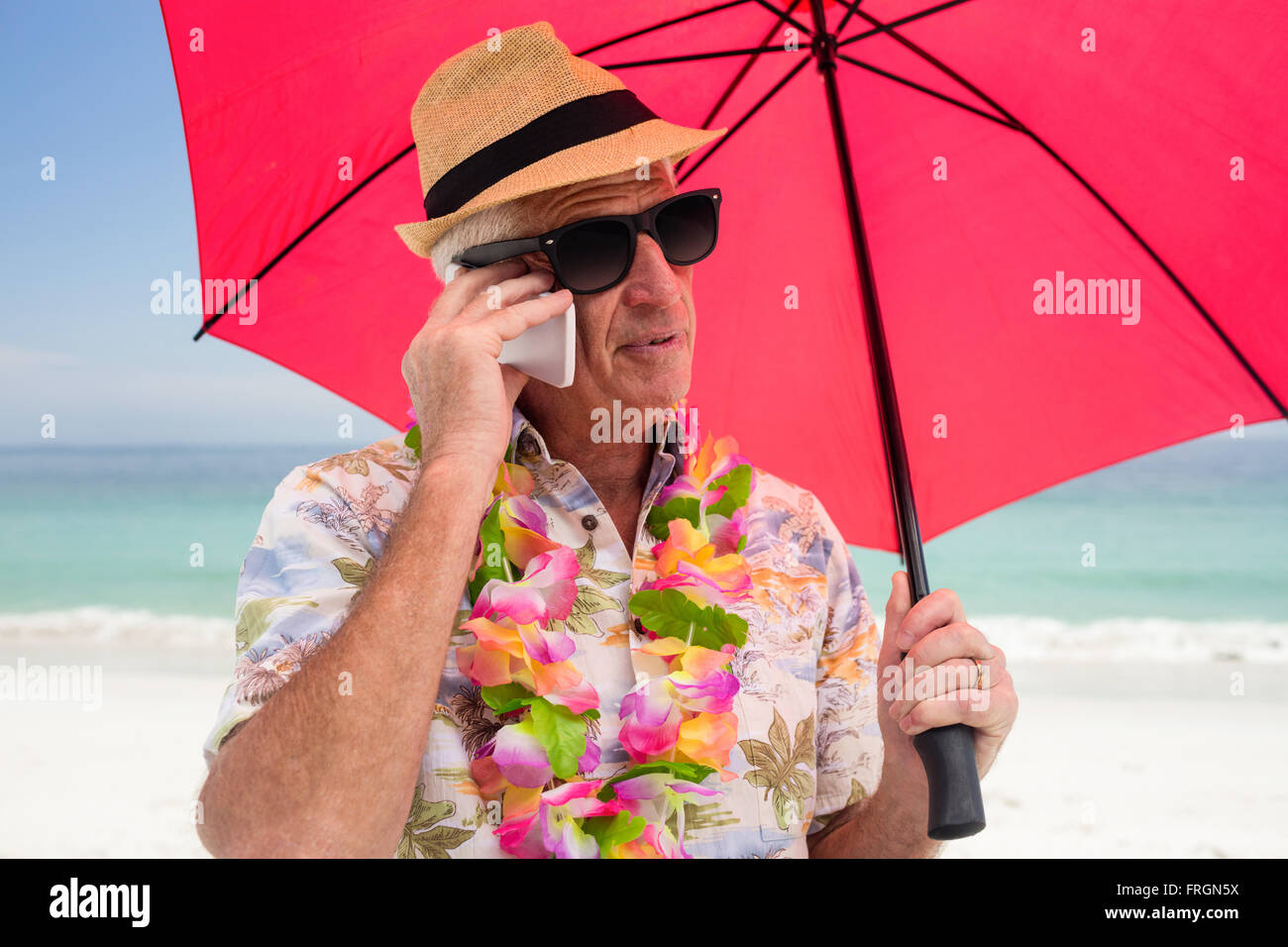 Senior man holding umbrella while talking on phone Stock Photo