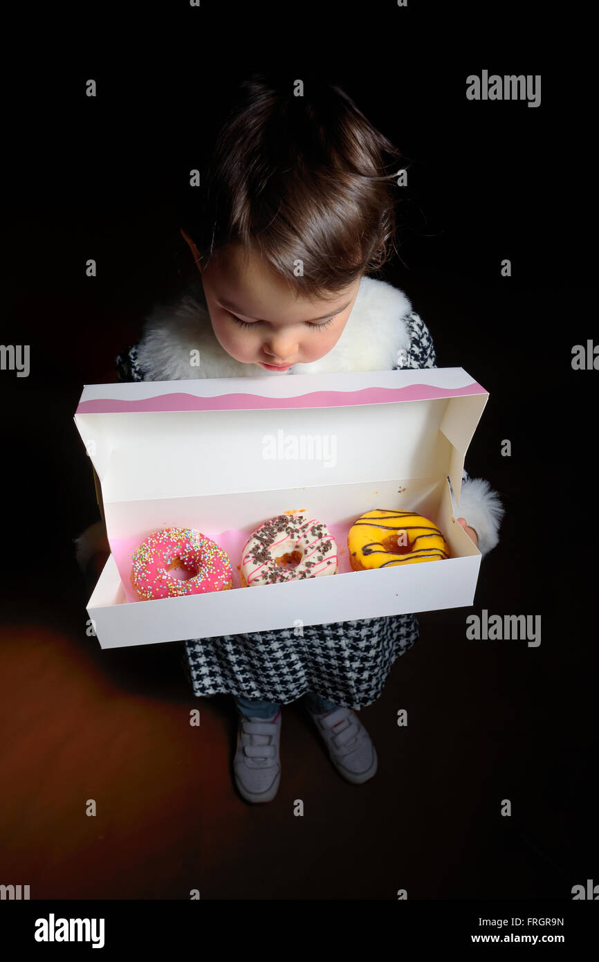 Little girl with sweet different types of donuts Stock Photo