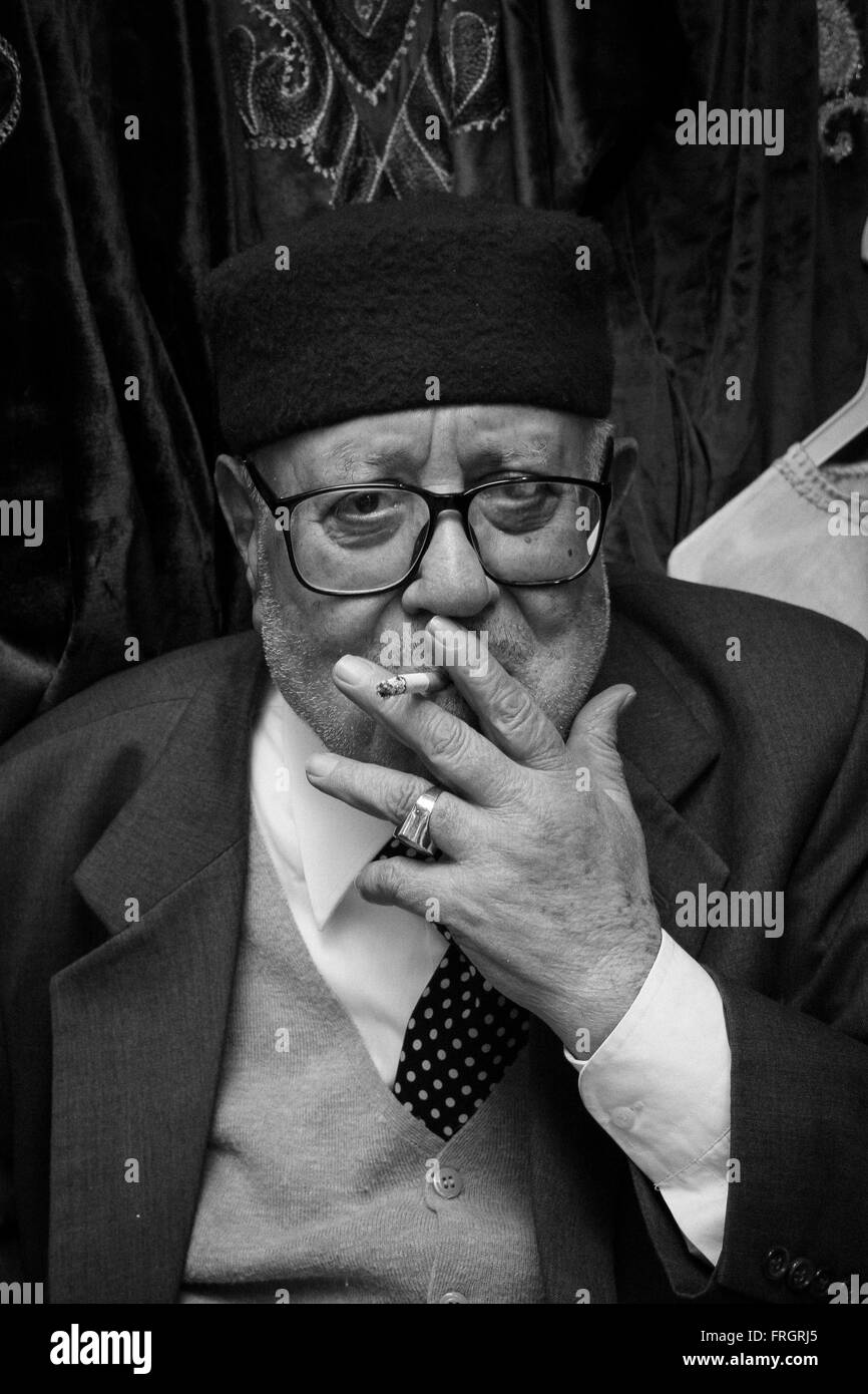 Head and shoulders portrait of Tunisian old man smoking a cigarette,TUNISIA Stock Photo