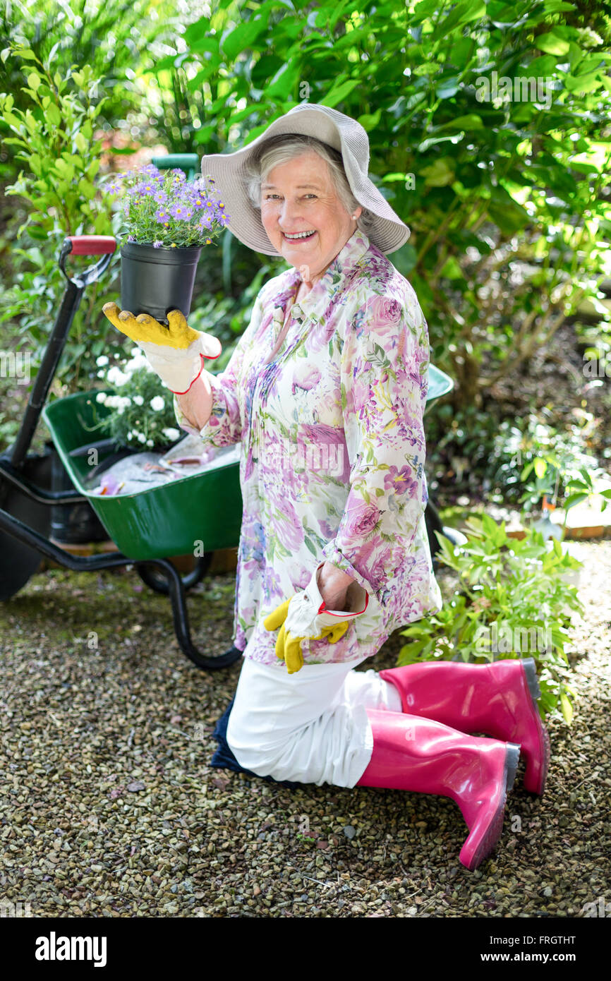 Cheerful senior woman holding potted plant in garden Stock Photo - Alamy