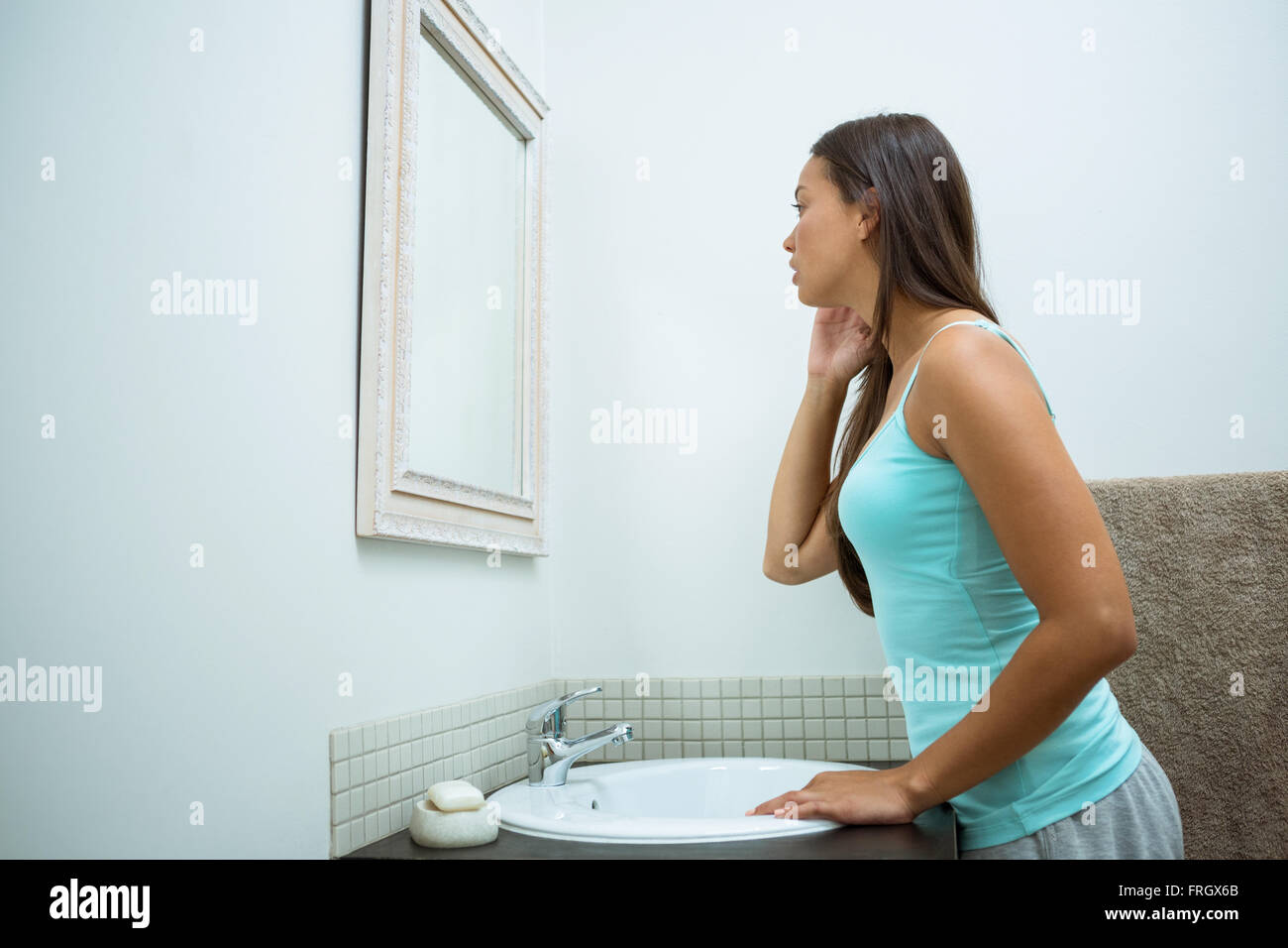 Woman checking her skin in bathroom Stock Photo