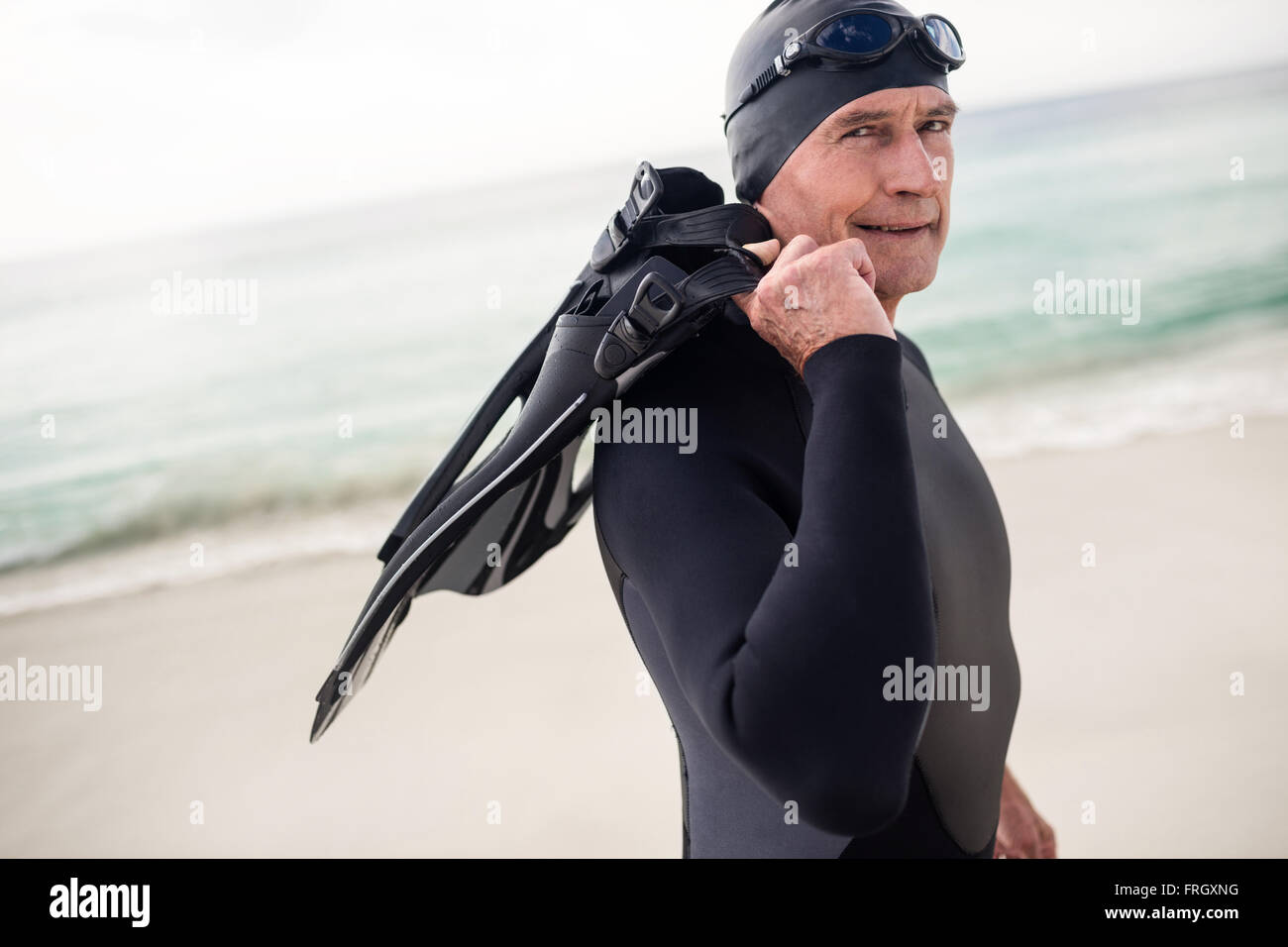 Senior man with flipper standing on beach Stock Photo