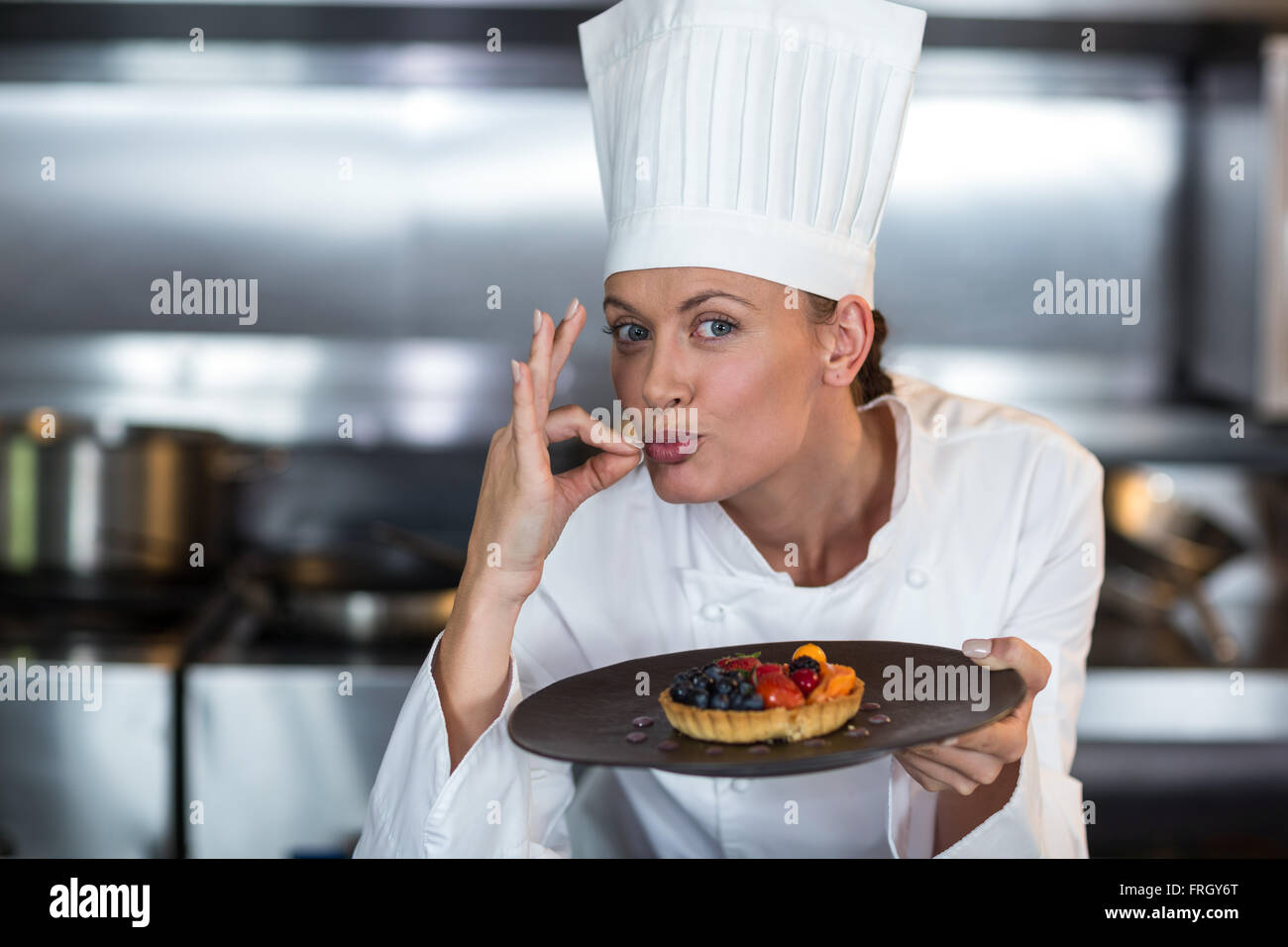 Portrait of female chef showing ok sign while holding dessert Stock Photo