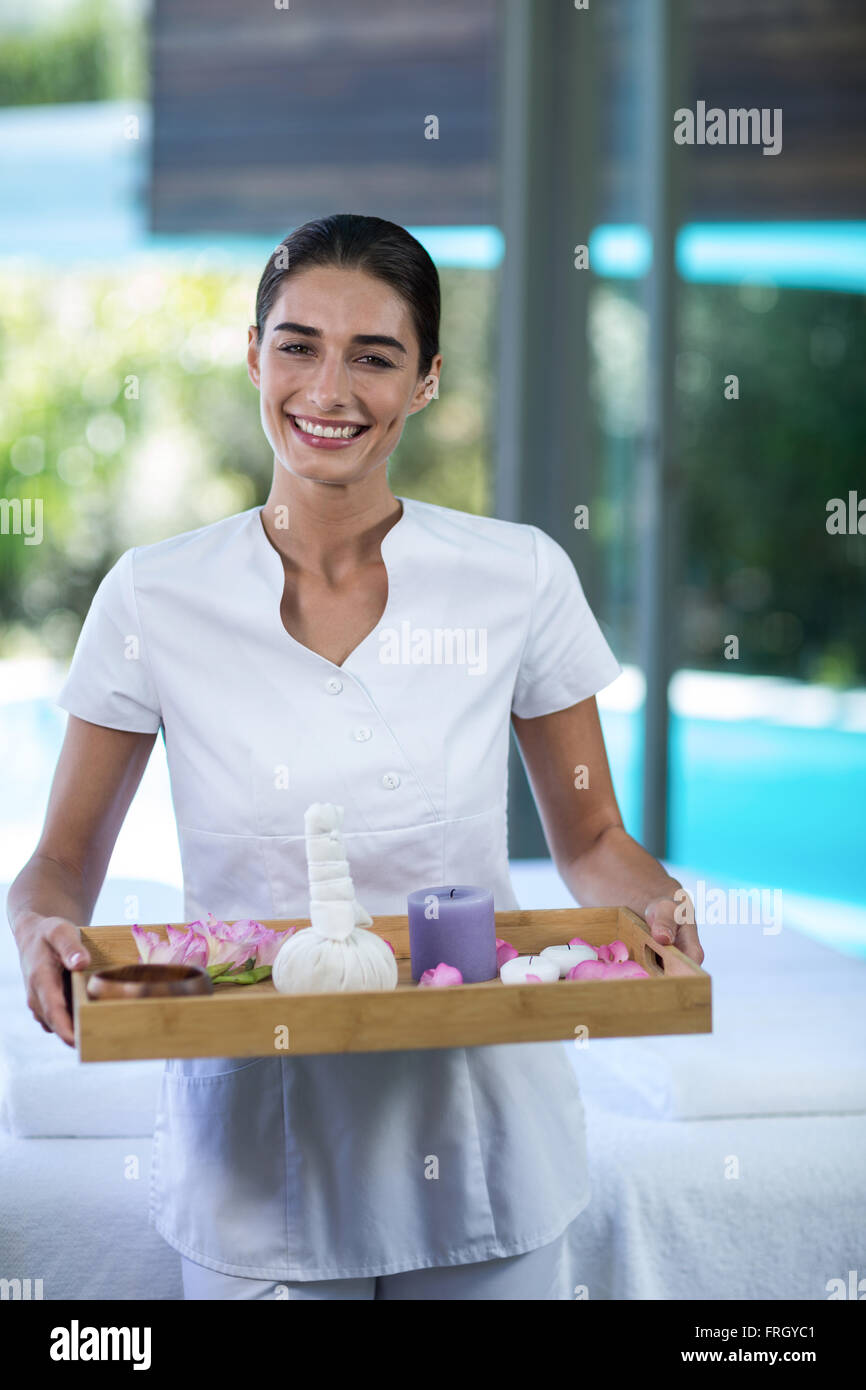 Female masseur holding a tray with spa therapy products Stock Photo