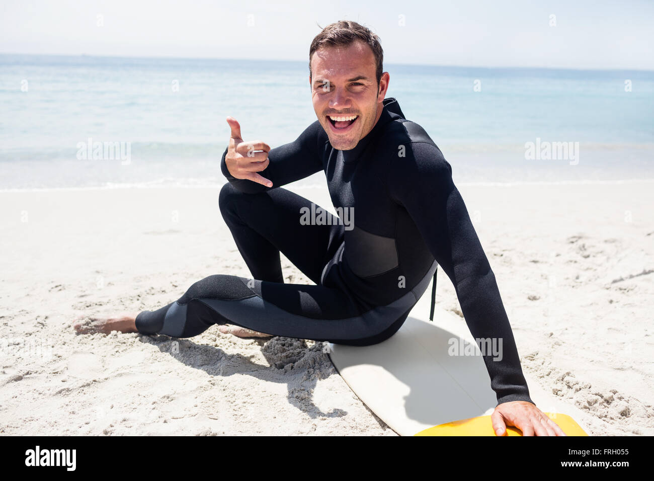Happy surfer in wetsuit sitting with surfboard on the beach Stock Photo Alamy