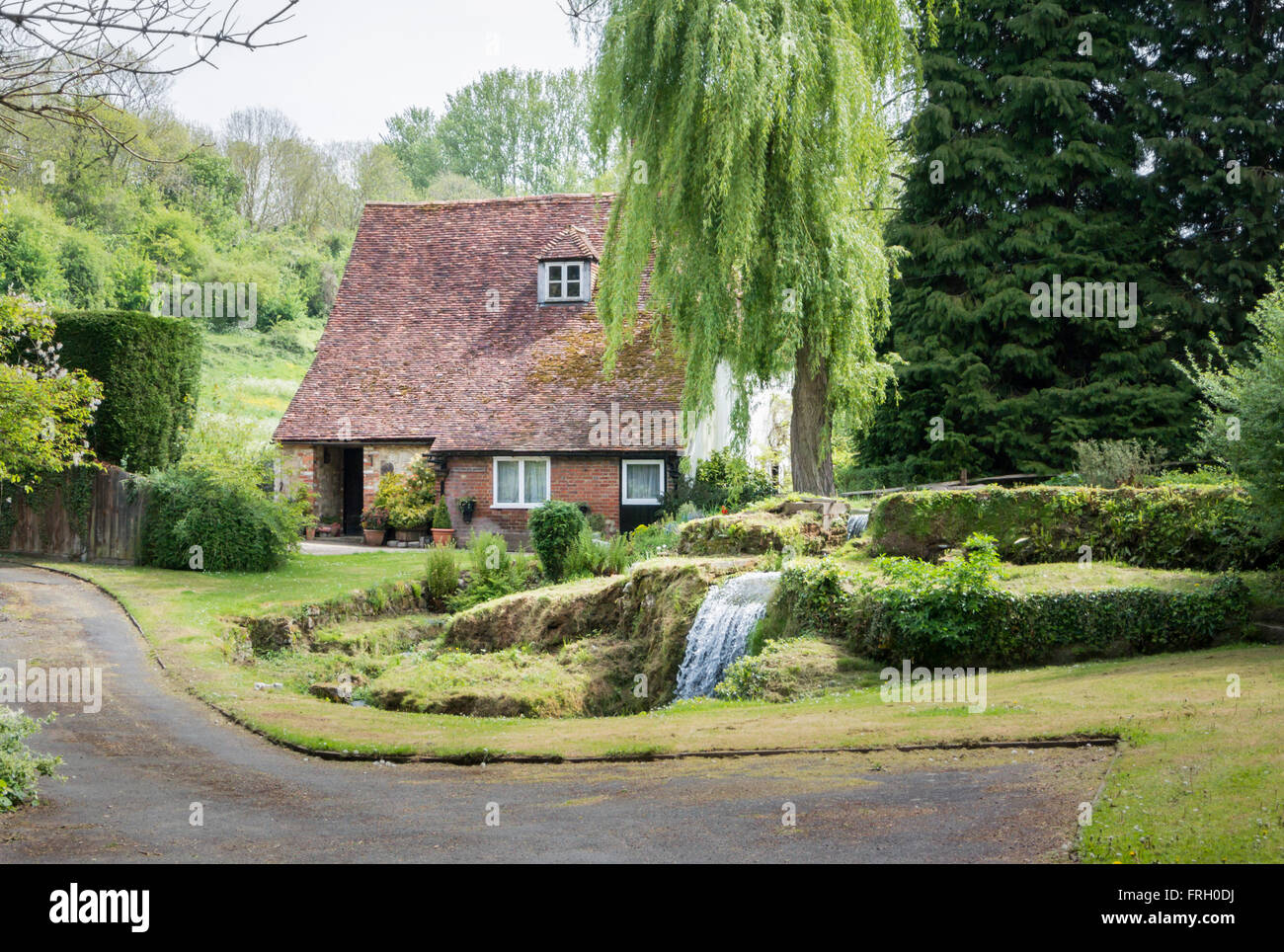 Old cottage with waterfall in the garden, in the pretty village of