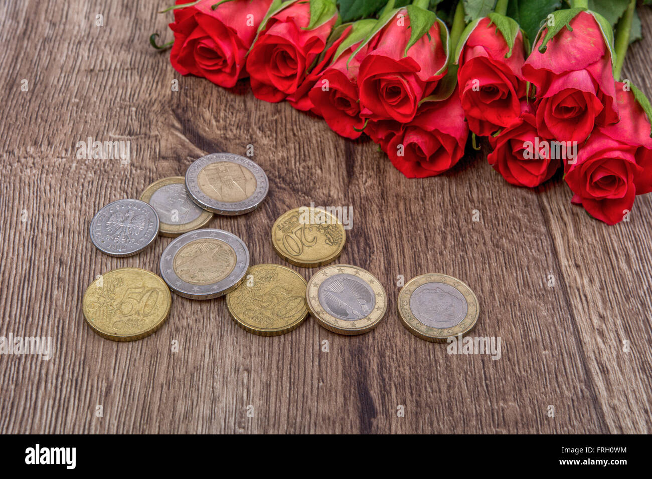 Euro coins and red roses on a wooden background Stock Photo - Alamy