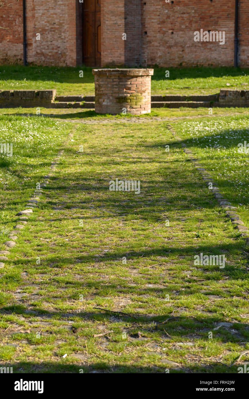 wishing well at the end of a path with focus on the path Stock Photo