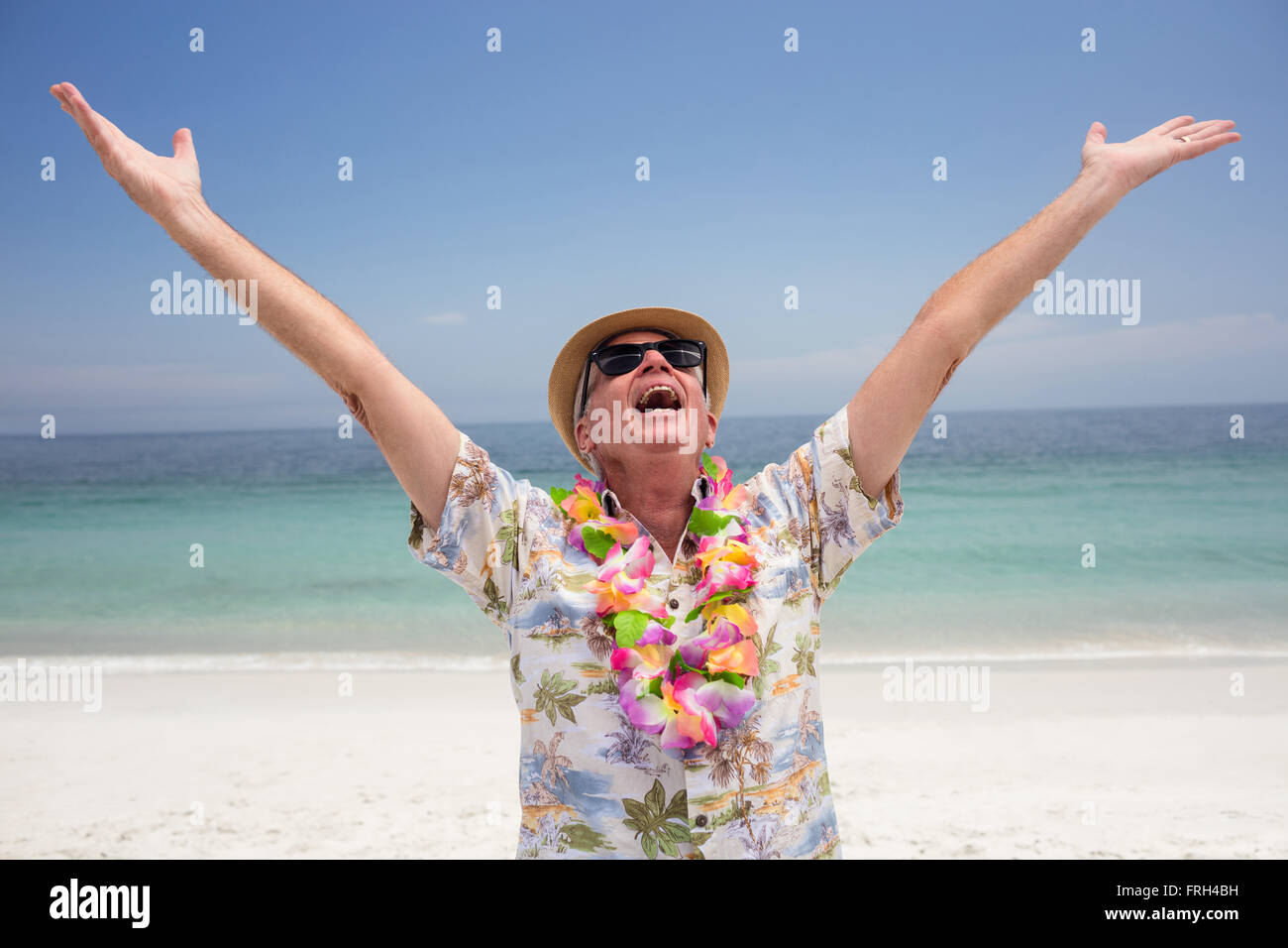 Happy senior man wearing flower garland and enjoying on the beach