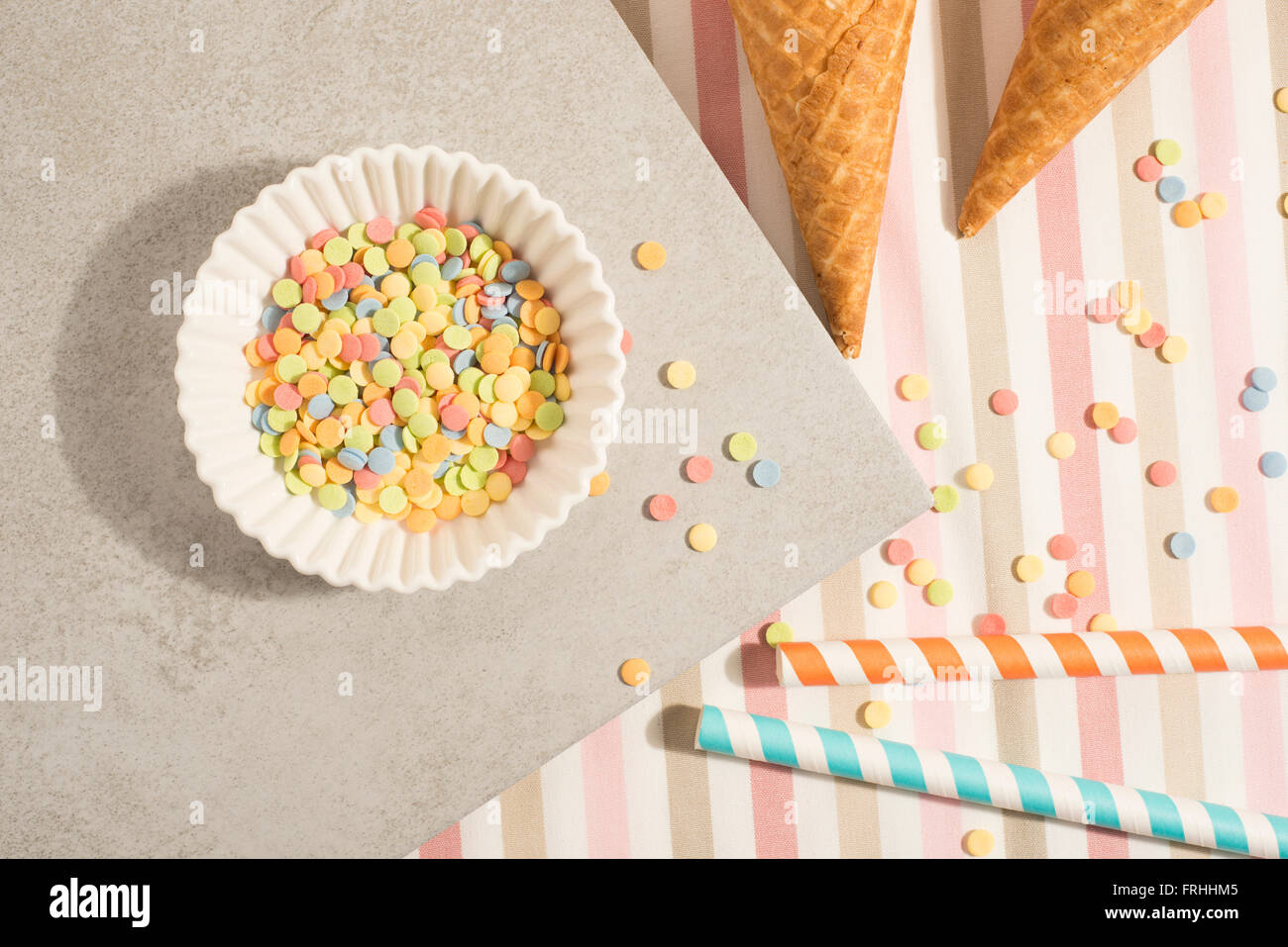 Colorful sugar sprinkles, straws and ice cream cones. Preparation for party or celebration. Concept of food styling. Stock Photo