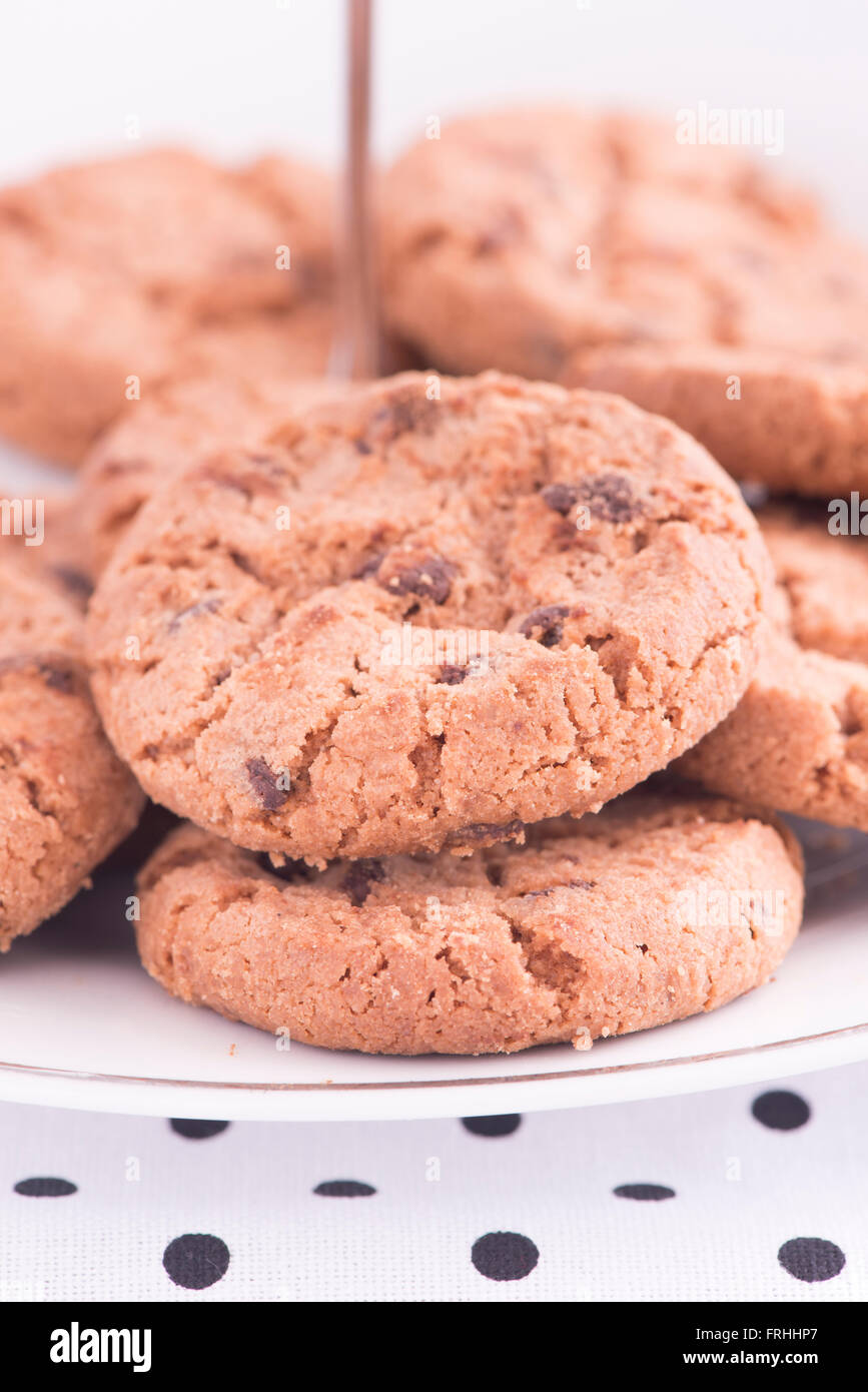 Chocolate chip cookies on plate in close up. Sweet food, dessert or snack. The cookies are served on a kitchen table. Stock Photo