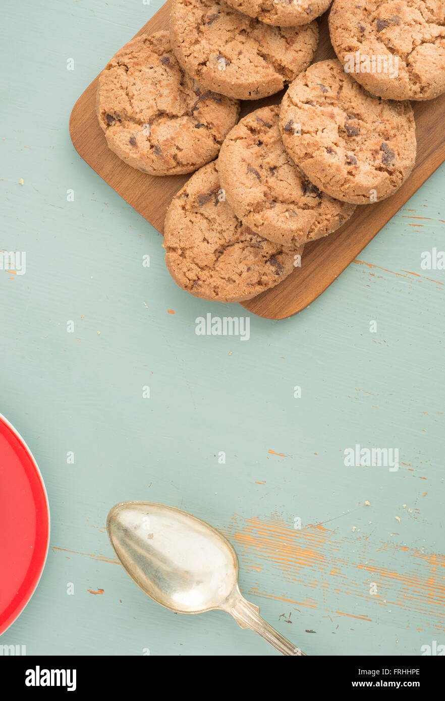 Chocolate chip cookies on wooden cutting board from above. Sweet food, dessert or snack. The cookies are on a kitchen table. Stock Photo