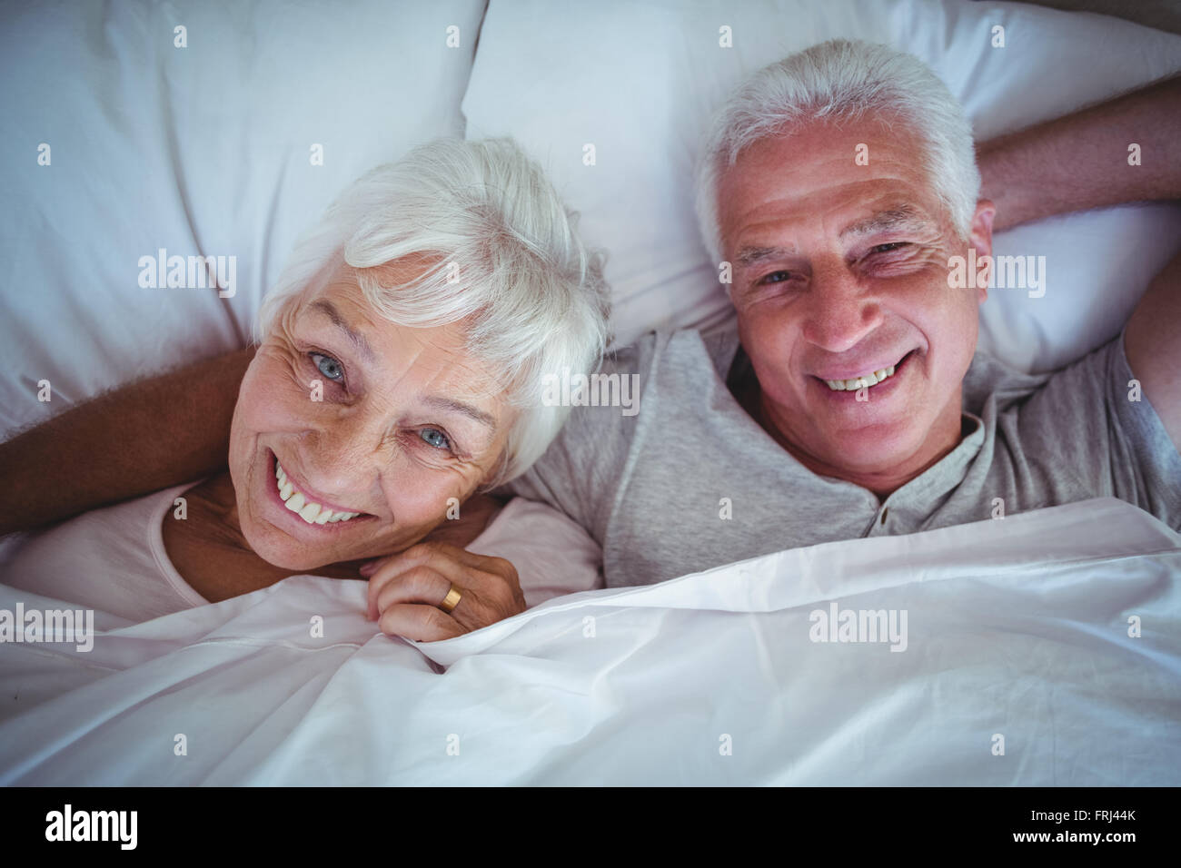 Happy senior couple lying on bed Stock Photo - Alamy