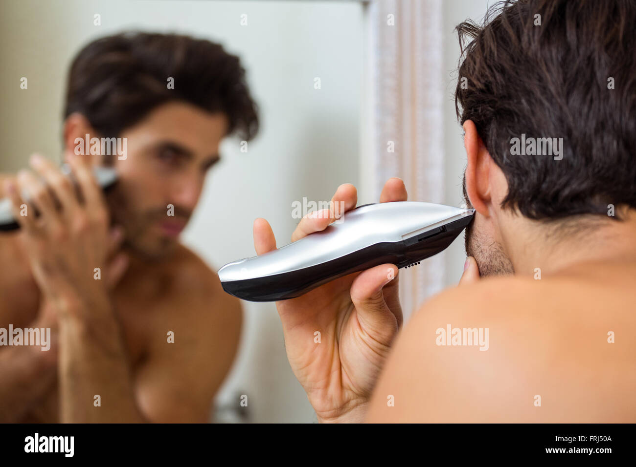 Young man shaving with trimmer Stock Photo Alamy