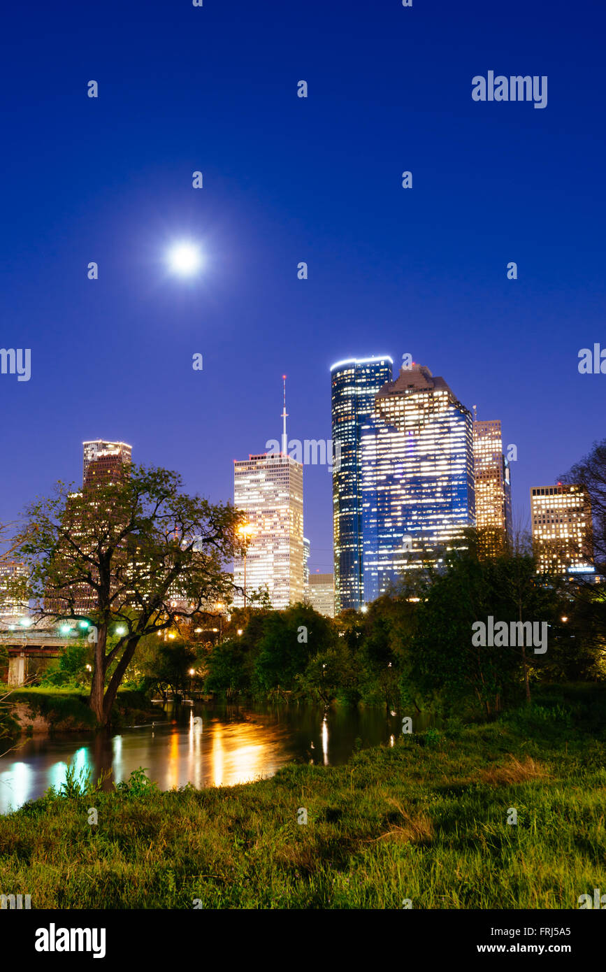 Houston downtown skyline at night with full moon as seen from Brazos river bank at Buffalo Bayou, Lindsy park, Texas, USA Stock Photo