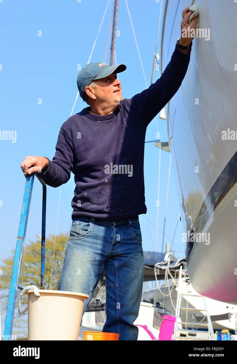 Boat owner hand polishing the hull of his boat on land in the marina at