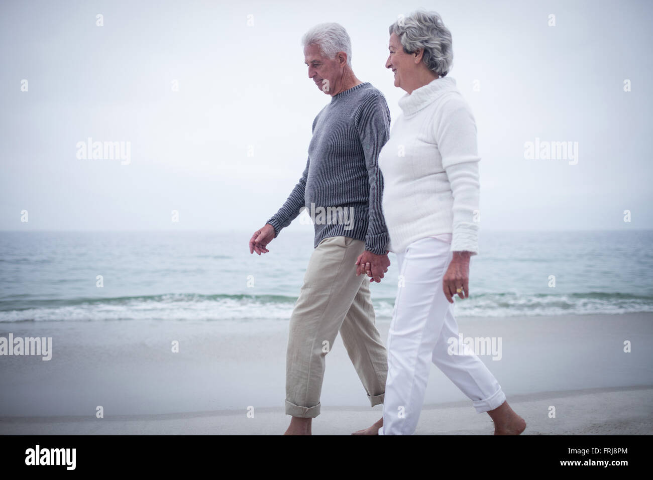 Senior couple holding hands and walking on the beach Stock Photo - Alamy