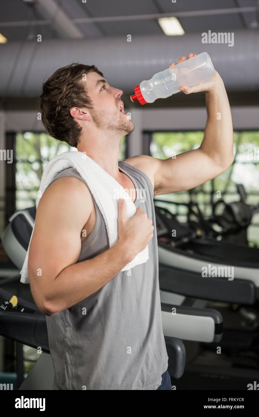 Man on treadmill drinking water at gym Stock Photo