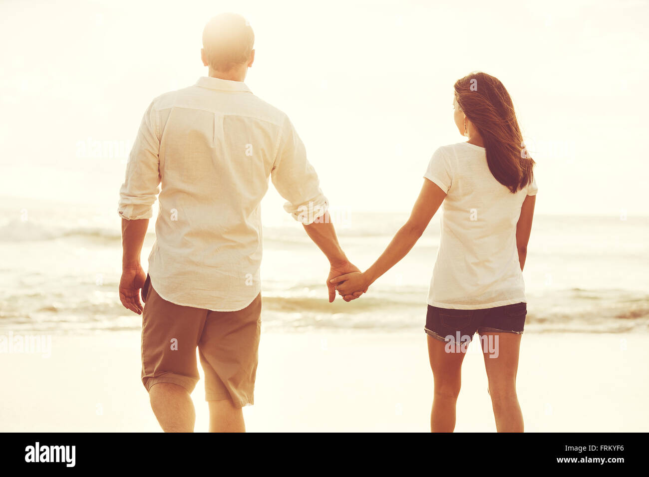 Happy romantic couple on the beach at sunset. Young lovers on vacation. Stock Photo
